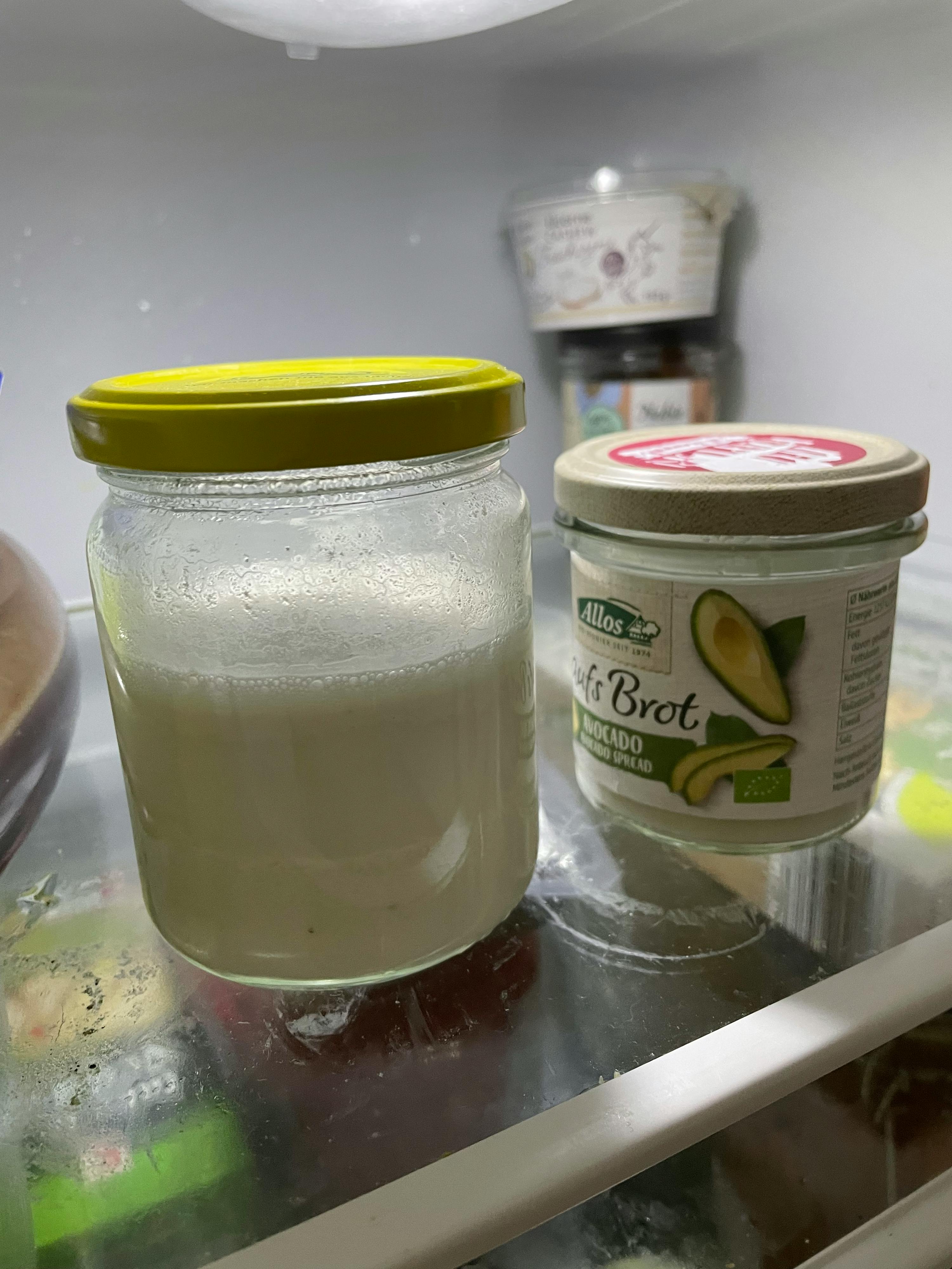 un pot d' huile d' avocat se trouve à côté d' un pot de yogourt dans un réfrigérateur