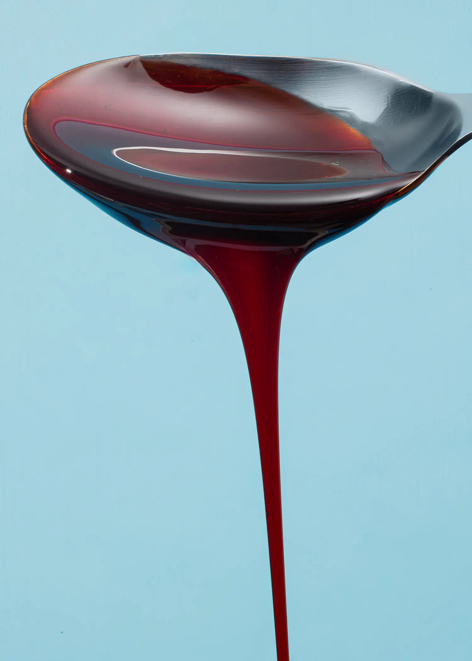 une cuillère remplie d' un liquide rouge sur fond bleu