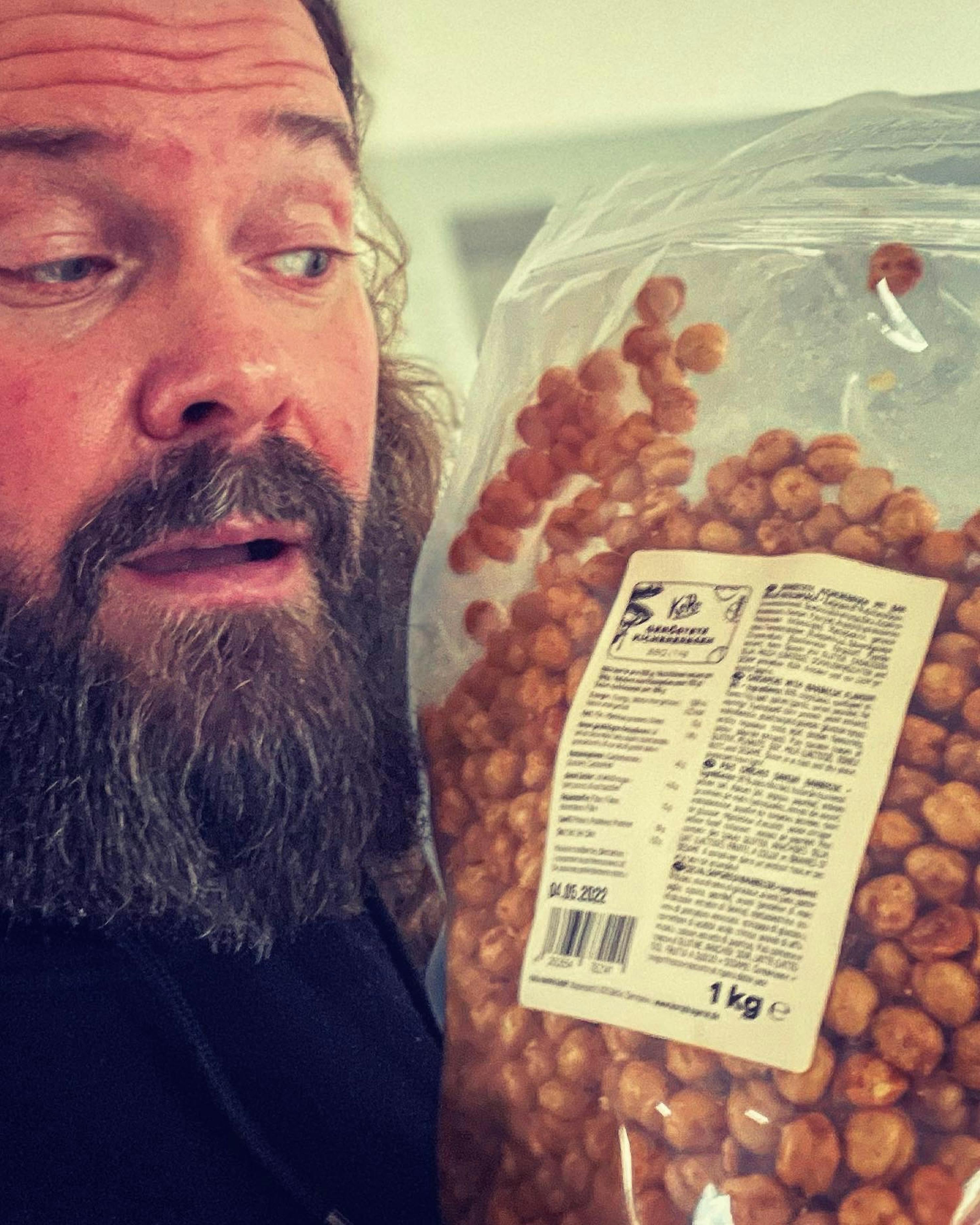a man with a beard is holding a bag of food that says 1 kg on it