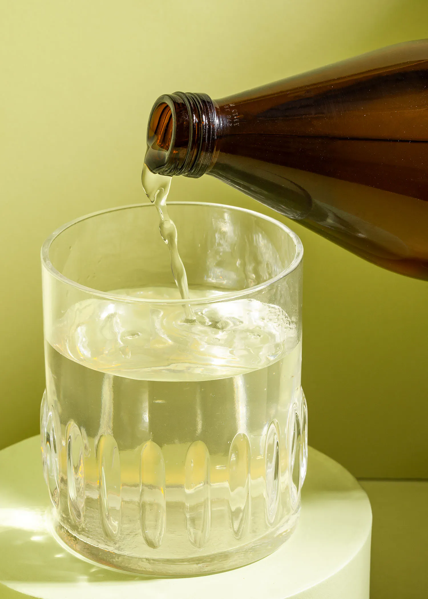 a glass of water is being poured from a bottle