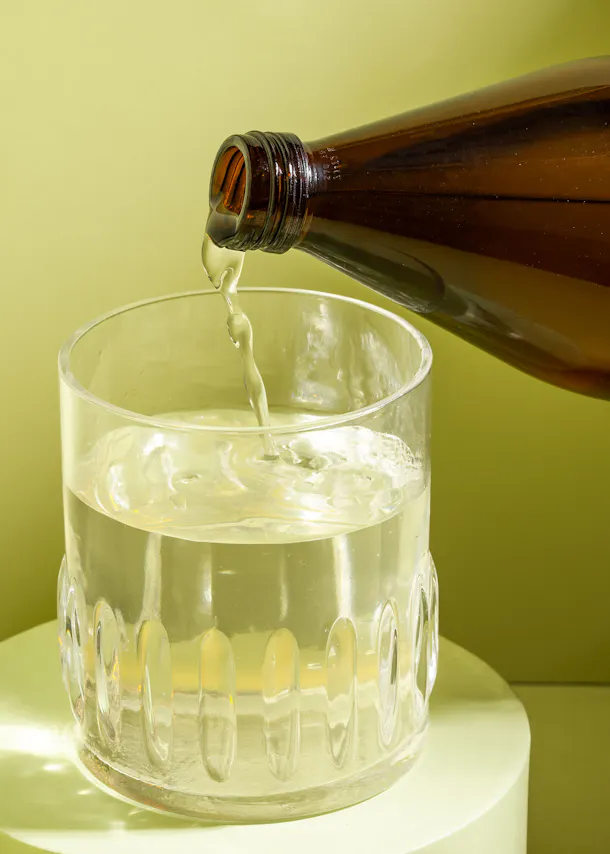 a glass of water is being poured from a bottle