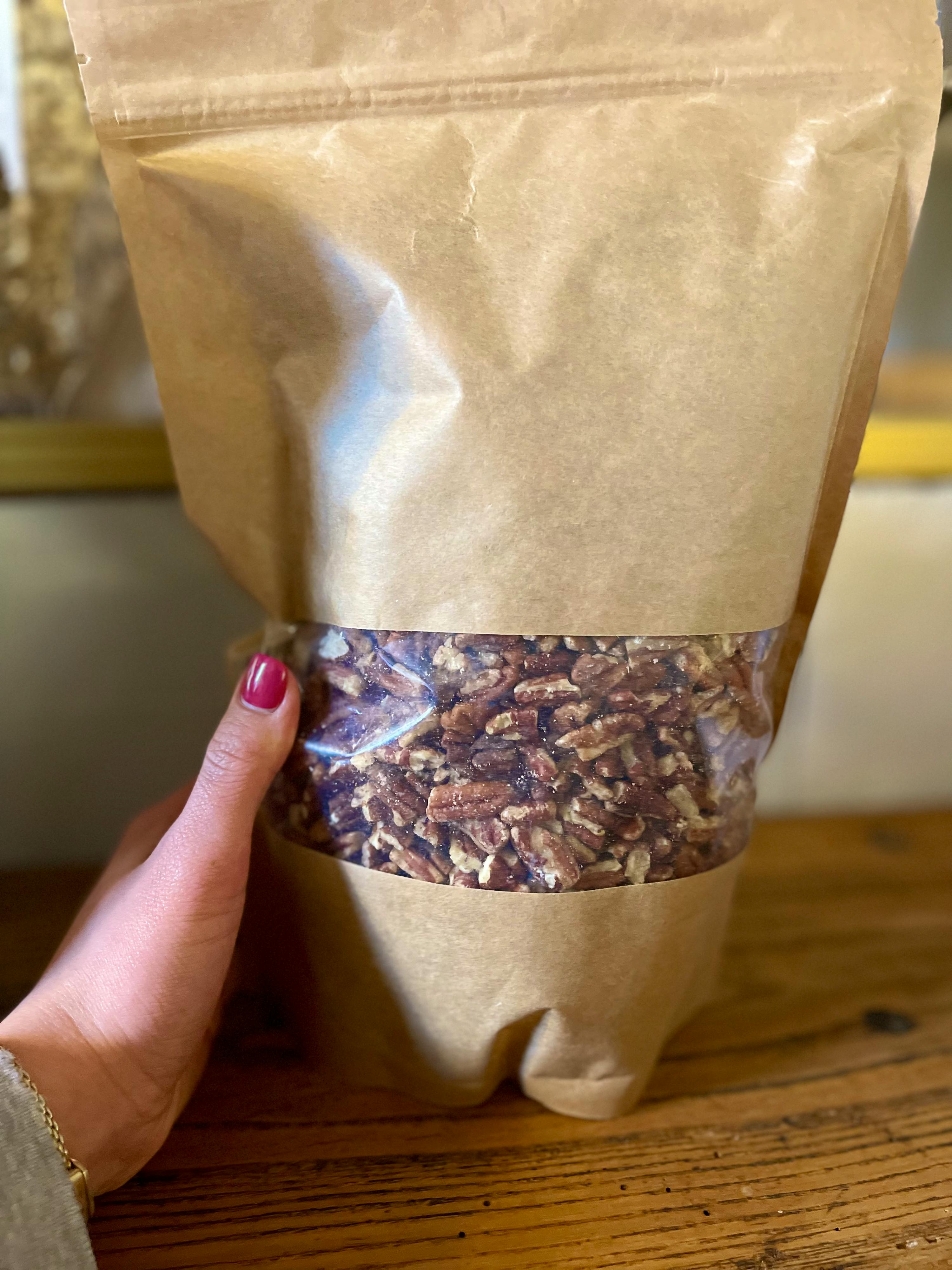 eine Person hält einen Plastikbeutel mit Pekannüssen darin