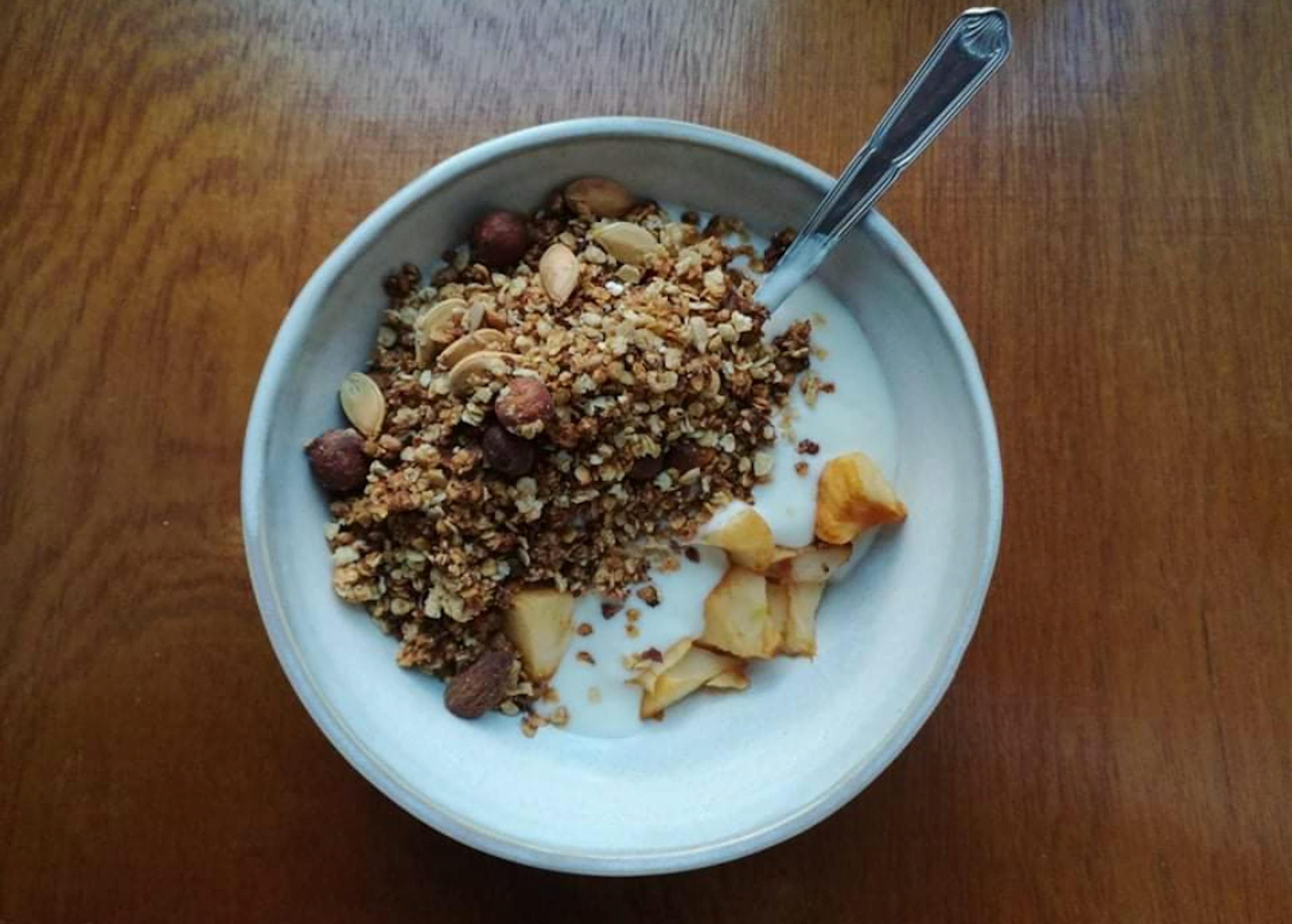 un bol blanc rempli de granola et de yogourt avec une cuillère