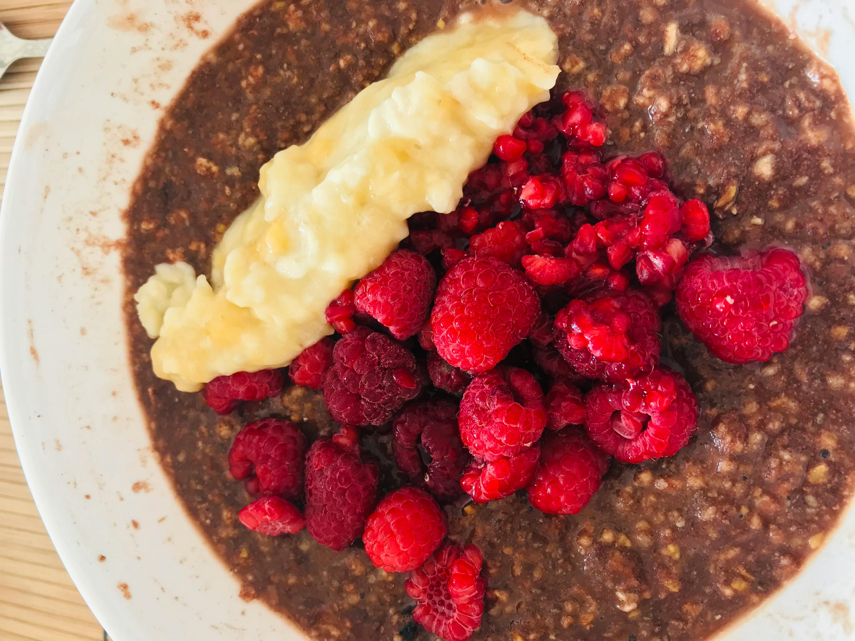 a bowl of oatmeal with raspberries and a banana on top