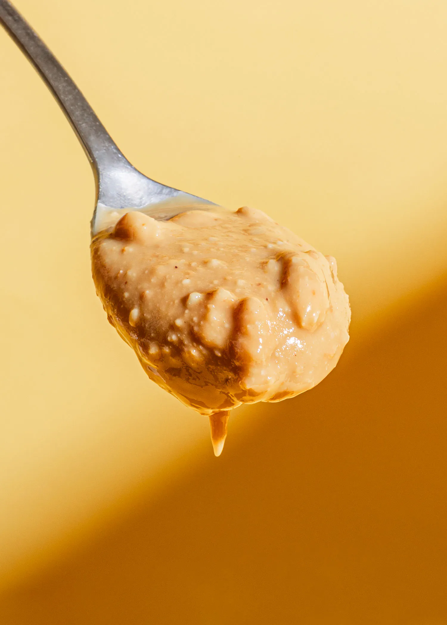une cuillère remplie de beurre d' arachide sur un fond jaune