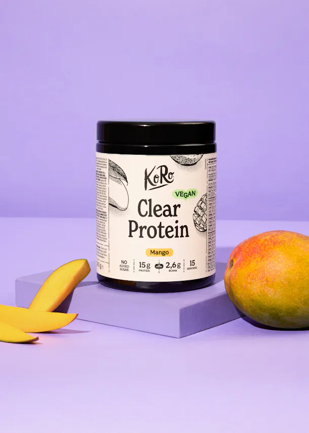 une bouteille de protéine transparente avec une mangue à côté