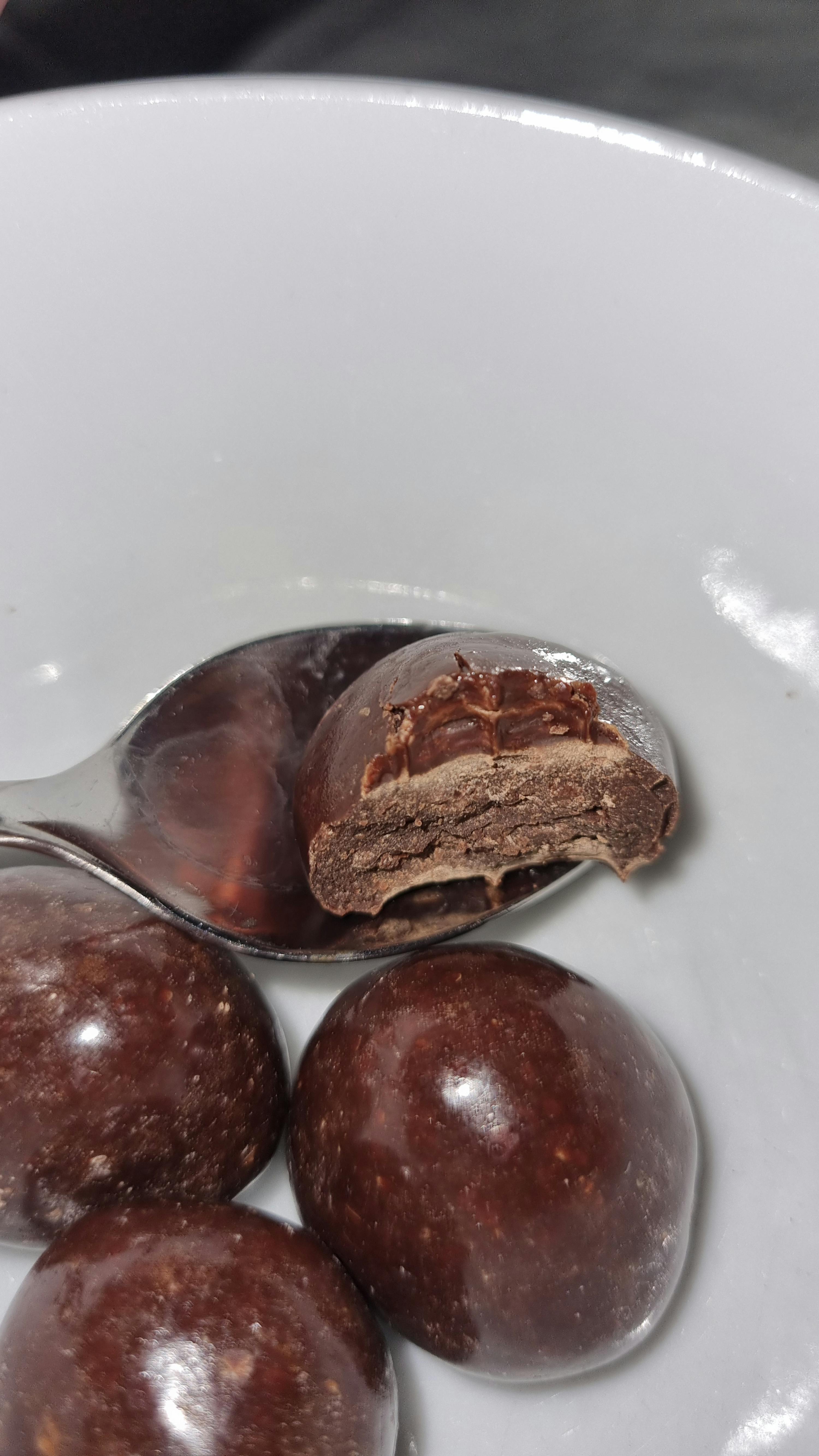 ein weißer Teller mit Schokoladenkugeln und einem Löffel darauf