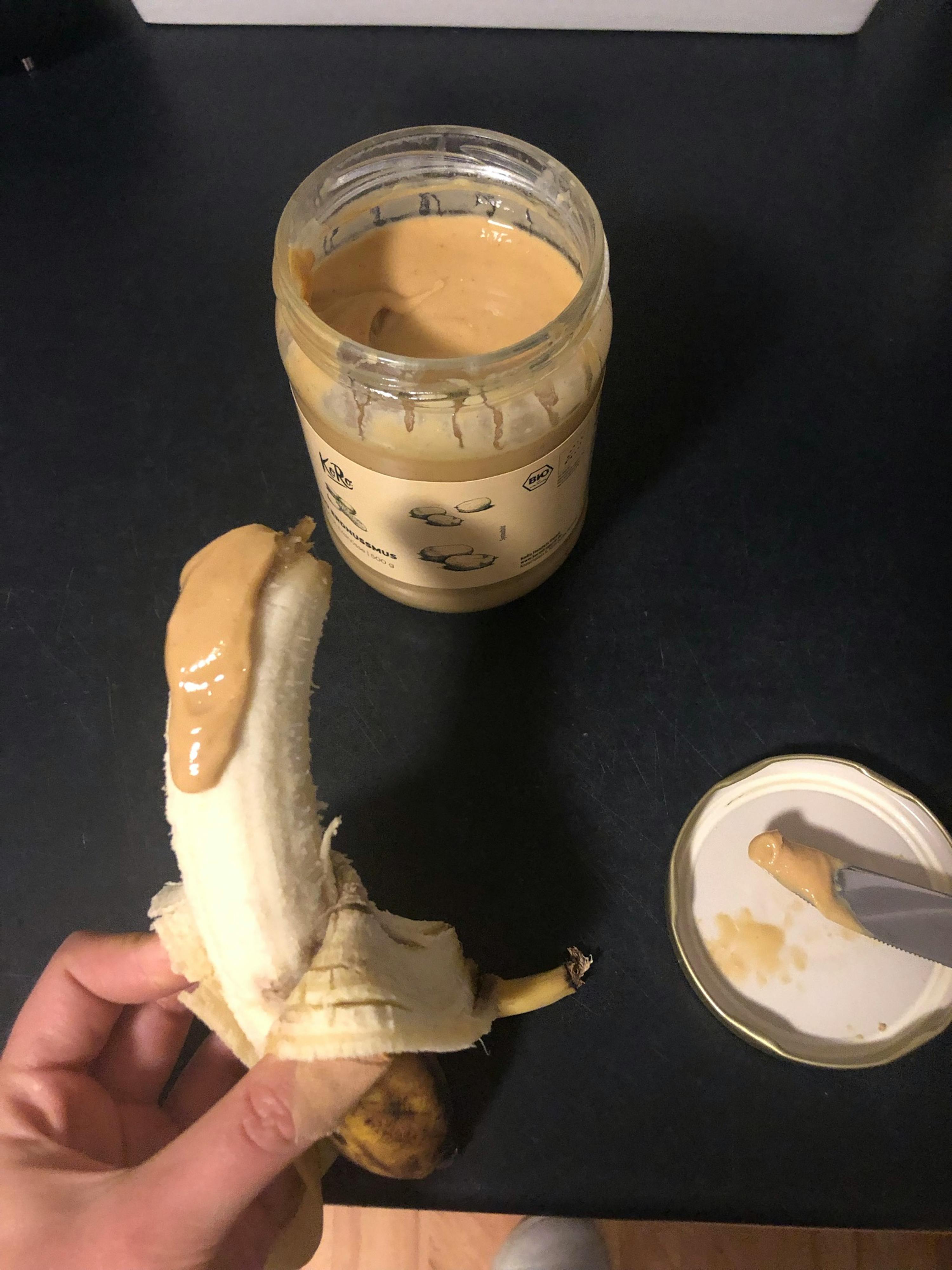 a banana is being peeled next to a jar of peanut butter