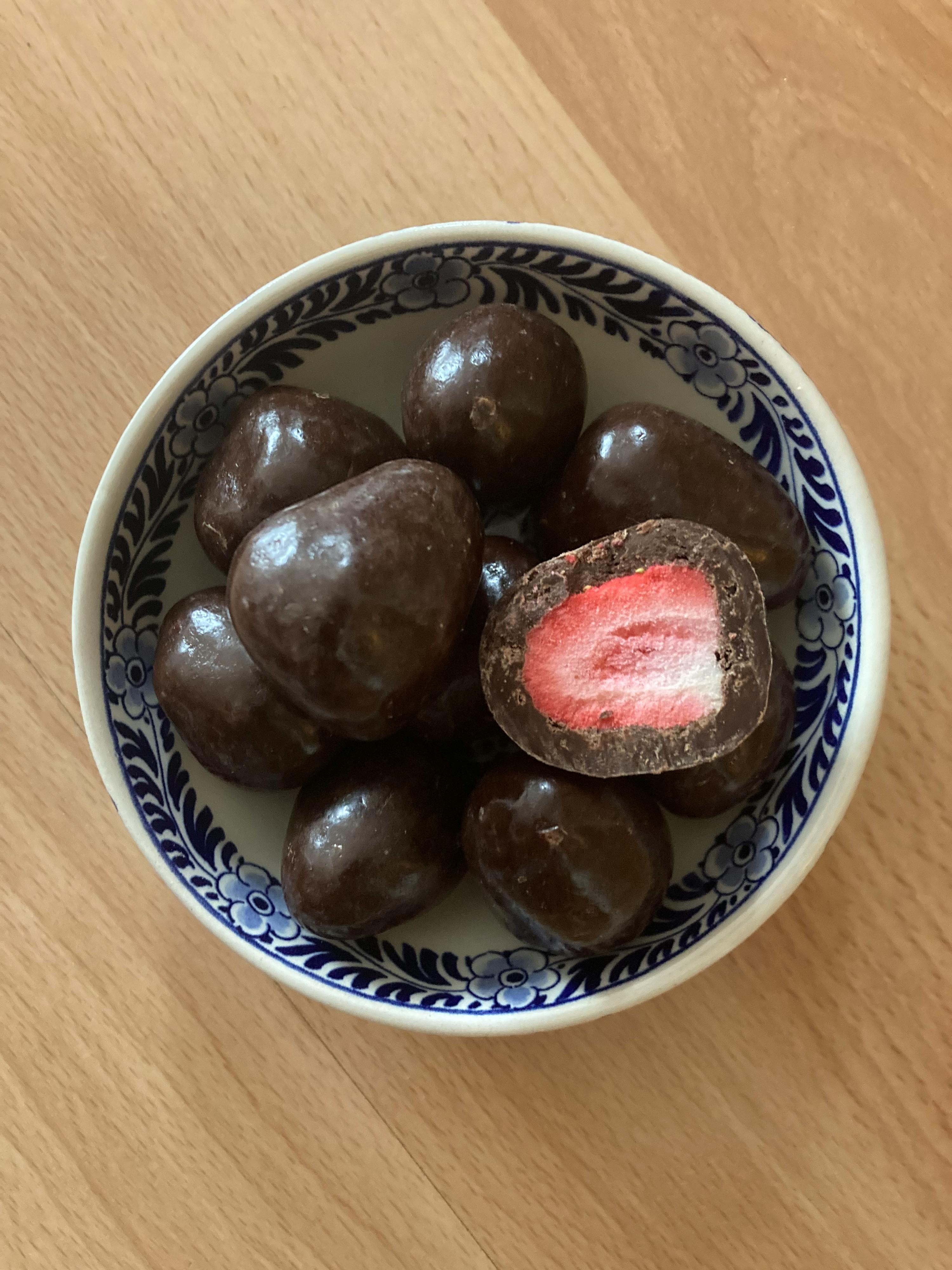 un bol bleu et blanc rempli de fraises enrobées de chocolat