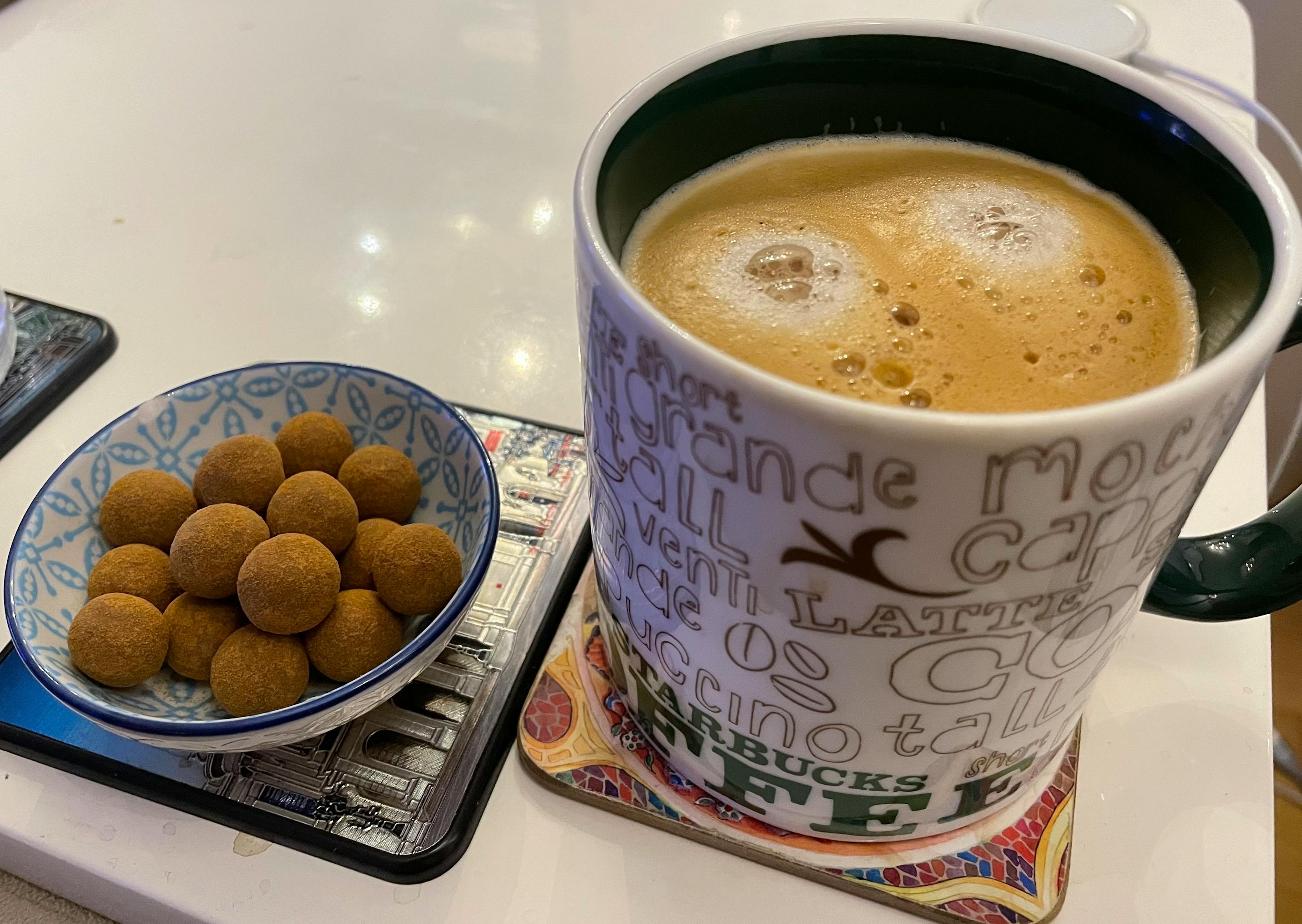 eine tasse kaffee steht neben einer schüssel mit nüssen