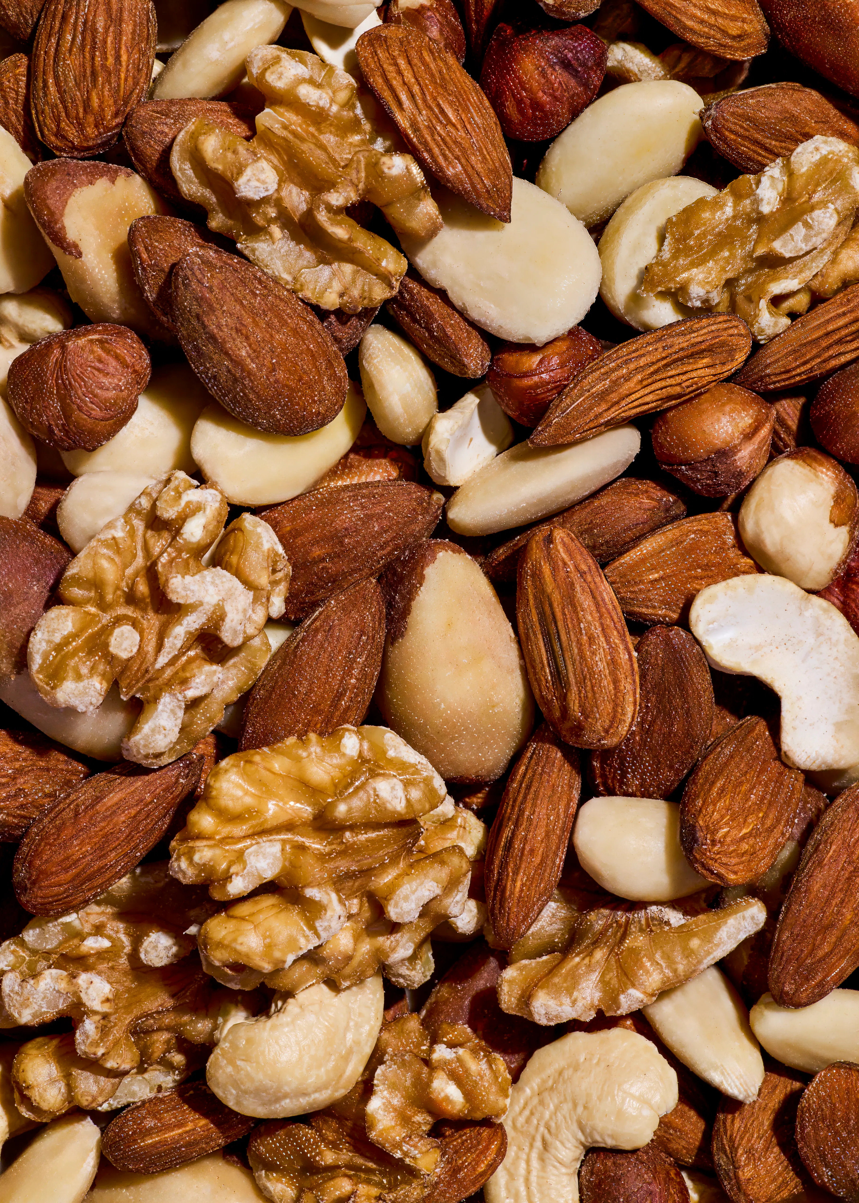 eine nahaufnahme einer mischung aus verschiedenen nüssen, darunter mandeln, walnüsse, haselnüsse, cashewkerne und paranüsse.