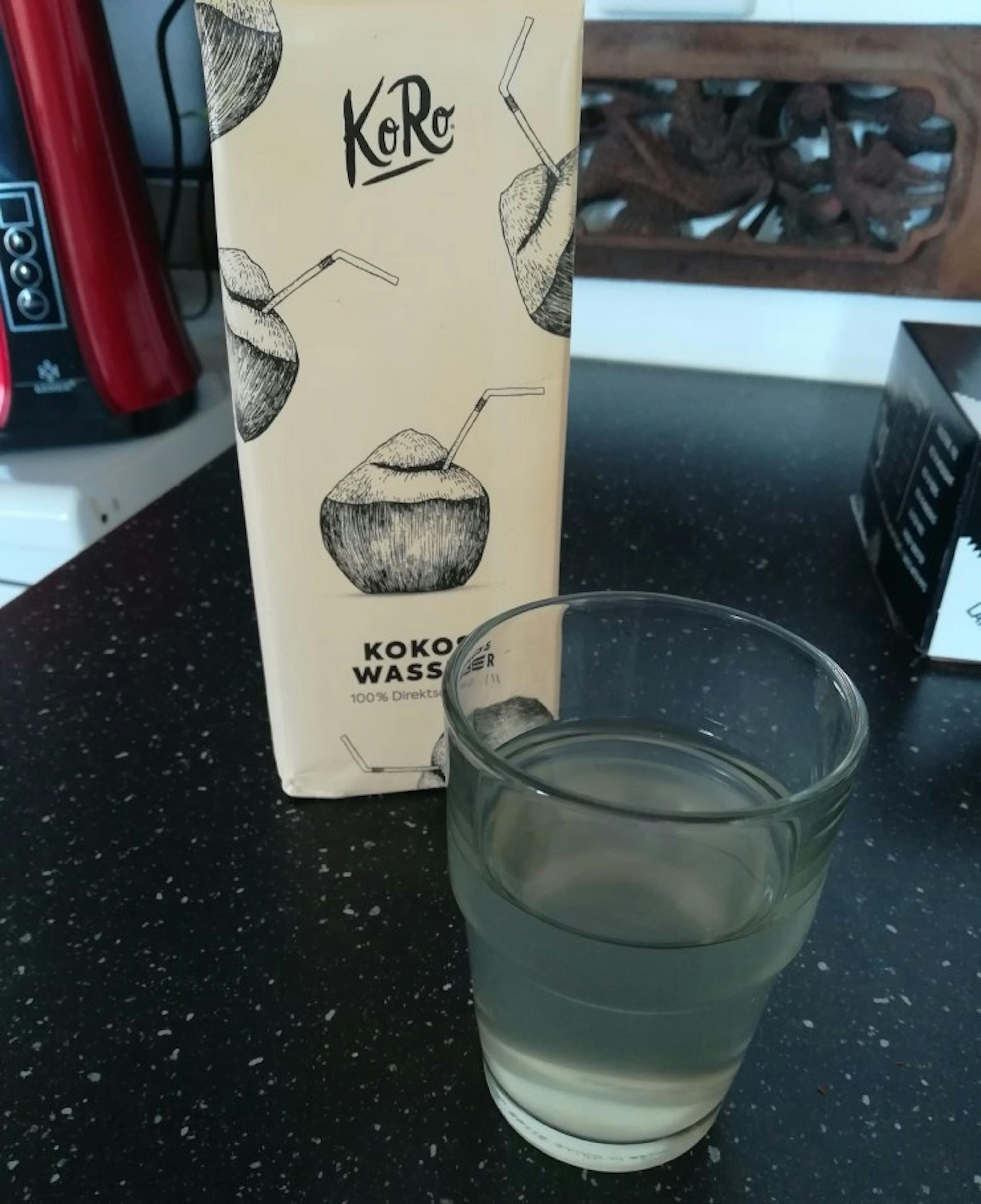 a carton of koro coconut water sits next to a glass