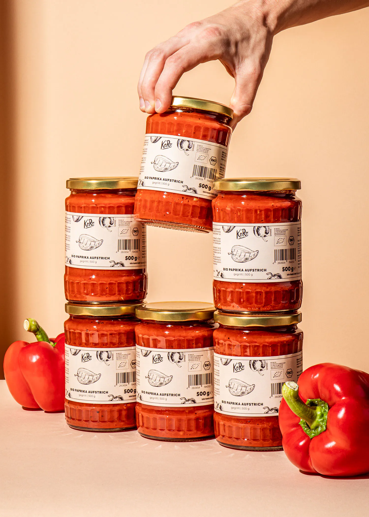 Eine Person stapelt sechs Gläser rote Soße aufeinander