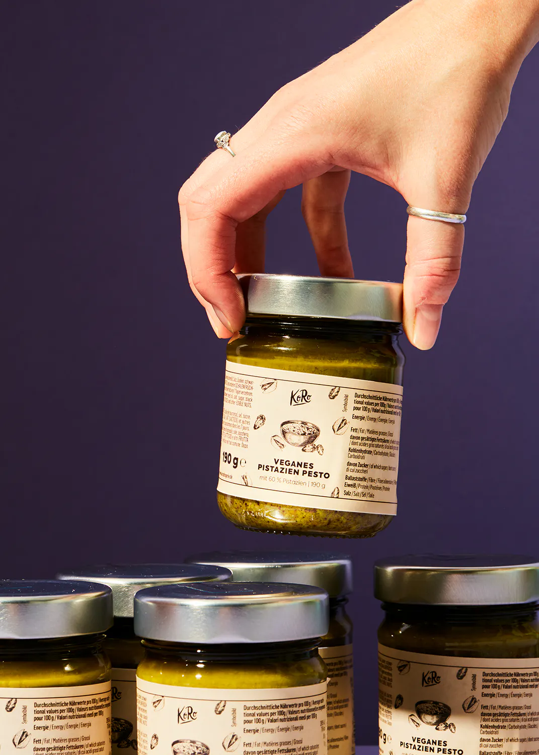 Eine Person hält ein Glas veganes Pistazienpesto in der Hand