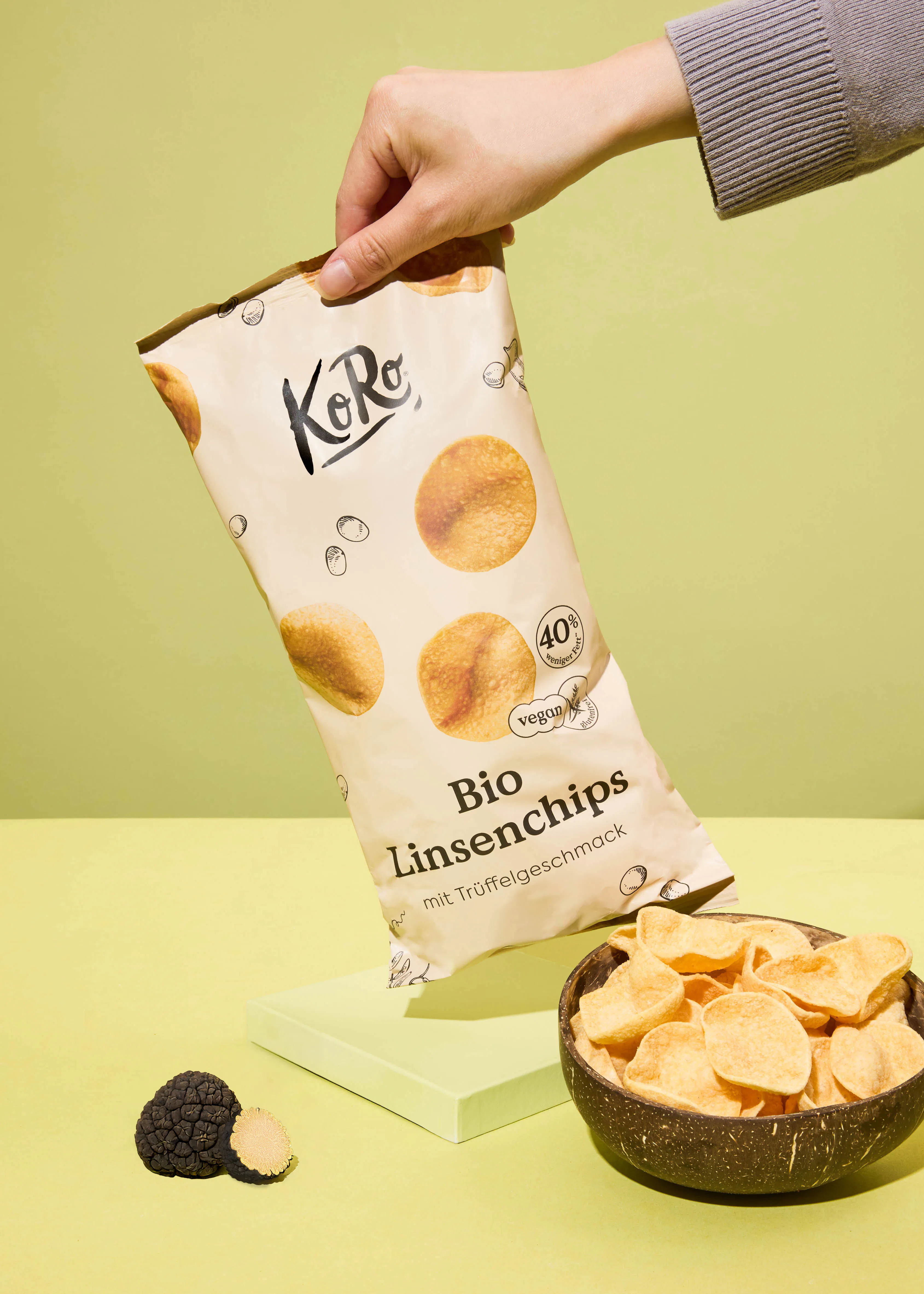 une personne tient un sac de chips bio à côté d' un bol de chips
