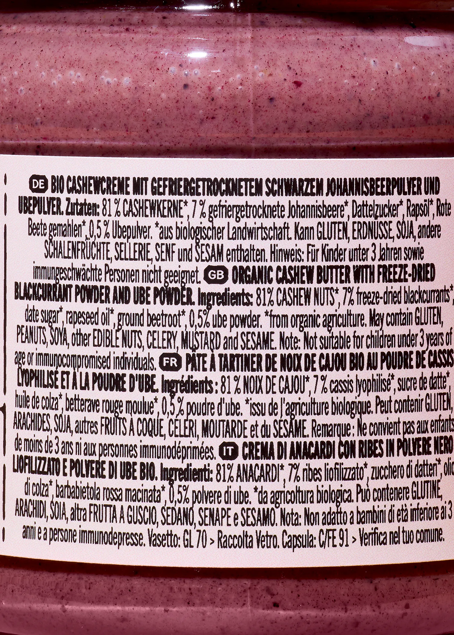 etiketten mit produktinformationen für eine bio-cashewcreme mit gefriergetrocknetem schwarzem johannisbeer- und ubepulver in deutscher, englischer, französischer und italienischer sprache.