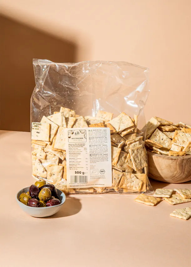 un sac de craquelins bio est posé à côté d' un bol d' olives