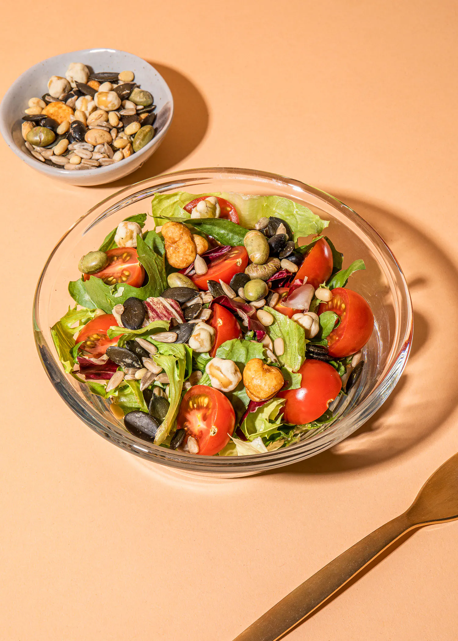 un bol de salade avec des tomates et des graines de citrouille