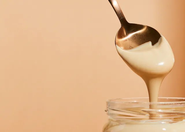 une cuillère remplit un bocal en verre d' un liquide blanc