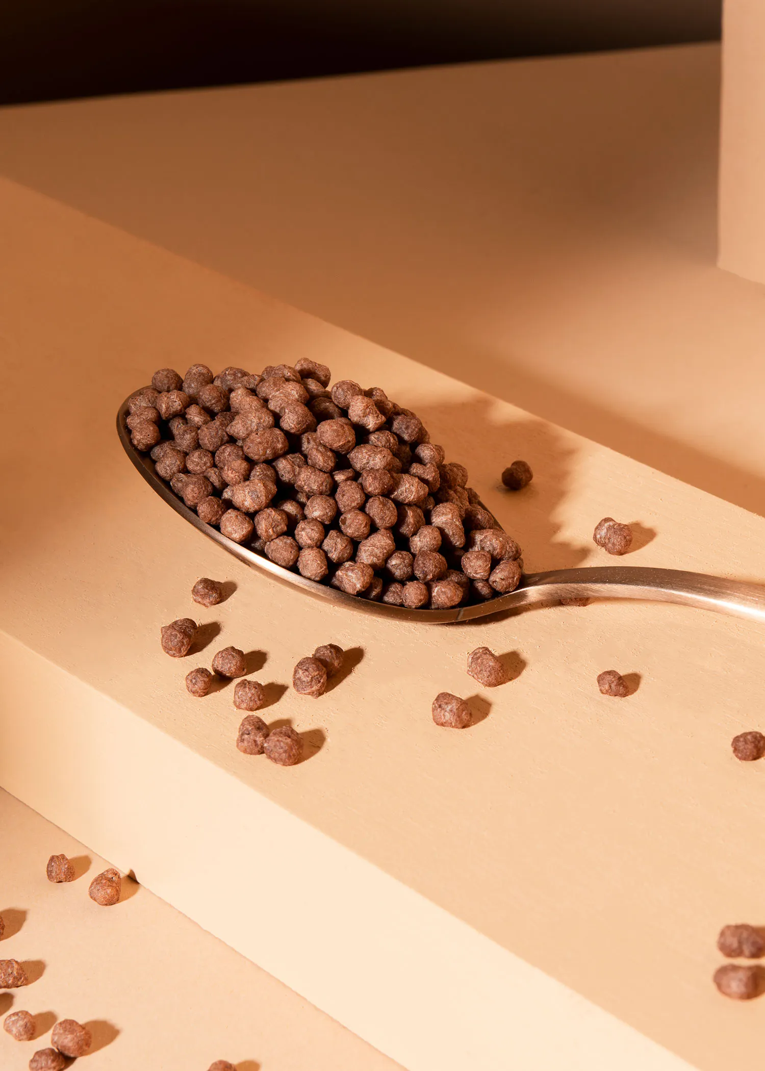 une cuillère remplie de céréales au chocolat sur une surface beige