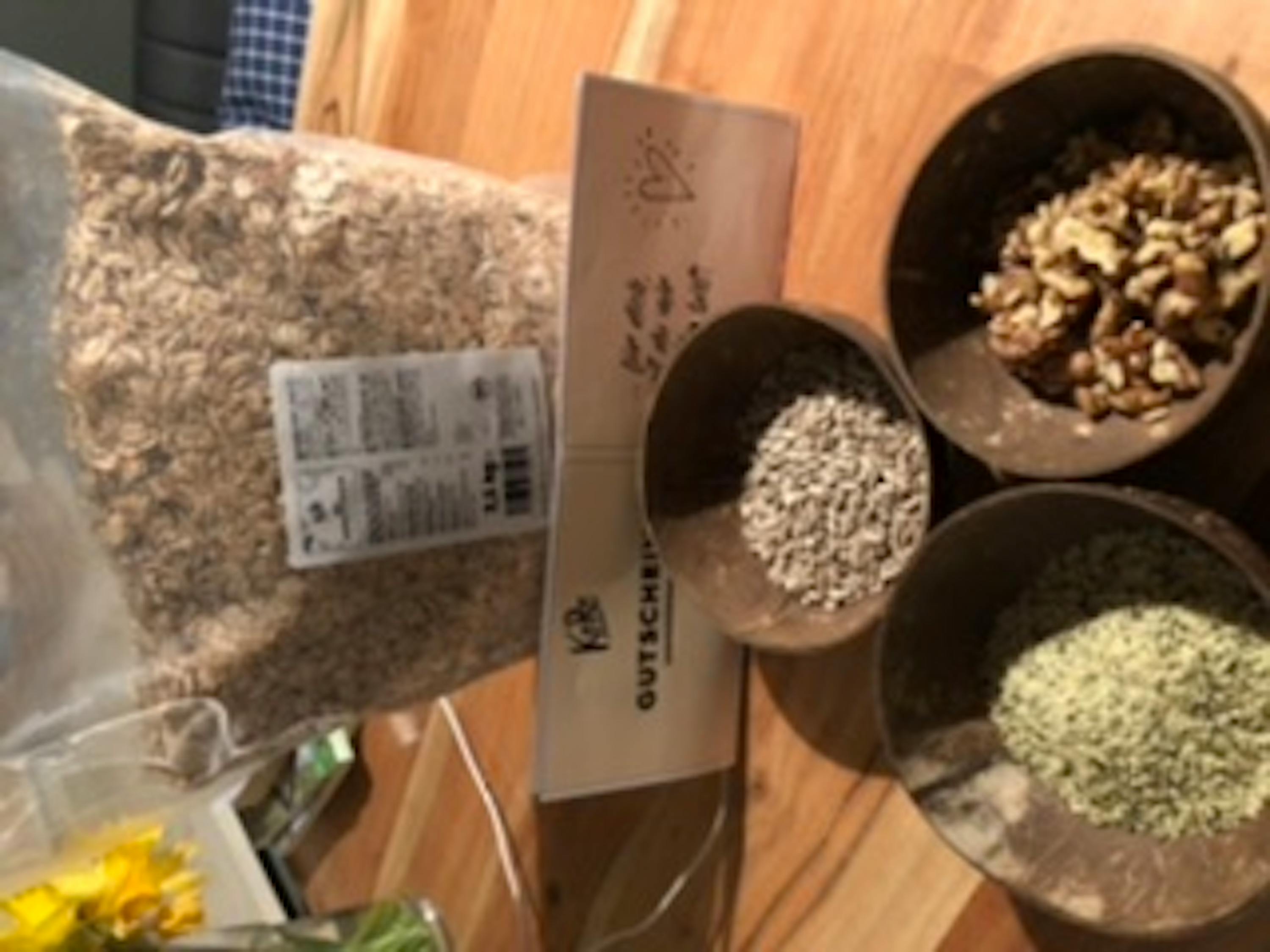 eine Tüte Haferflocken steht auf einem Holztisch neben einer Tüte Walnüsse