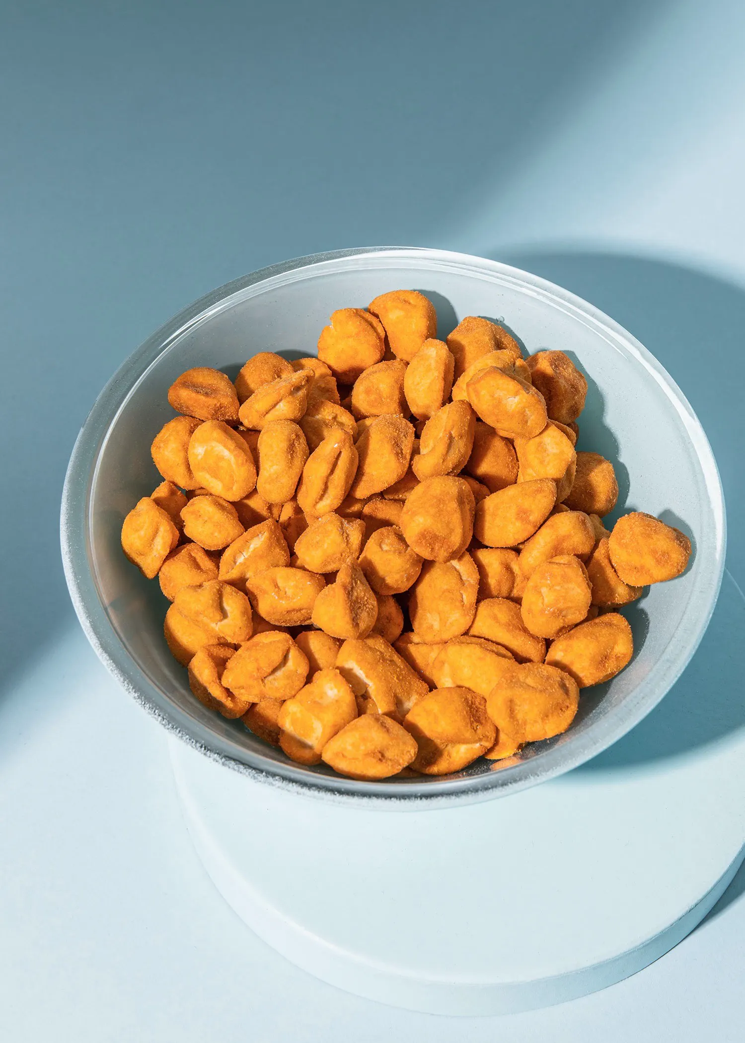 un bol blanc rempli de cacahuètes frites sur une surface bleue