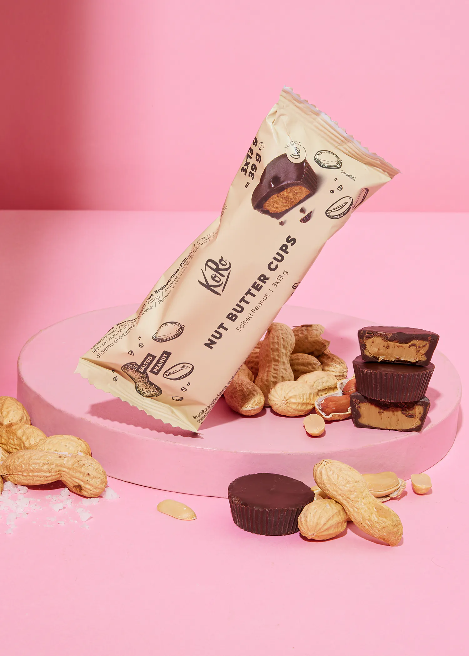 un paquet de tasses de beurre d' arachide avec des cacahuètes sur une table rose