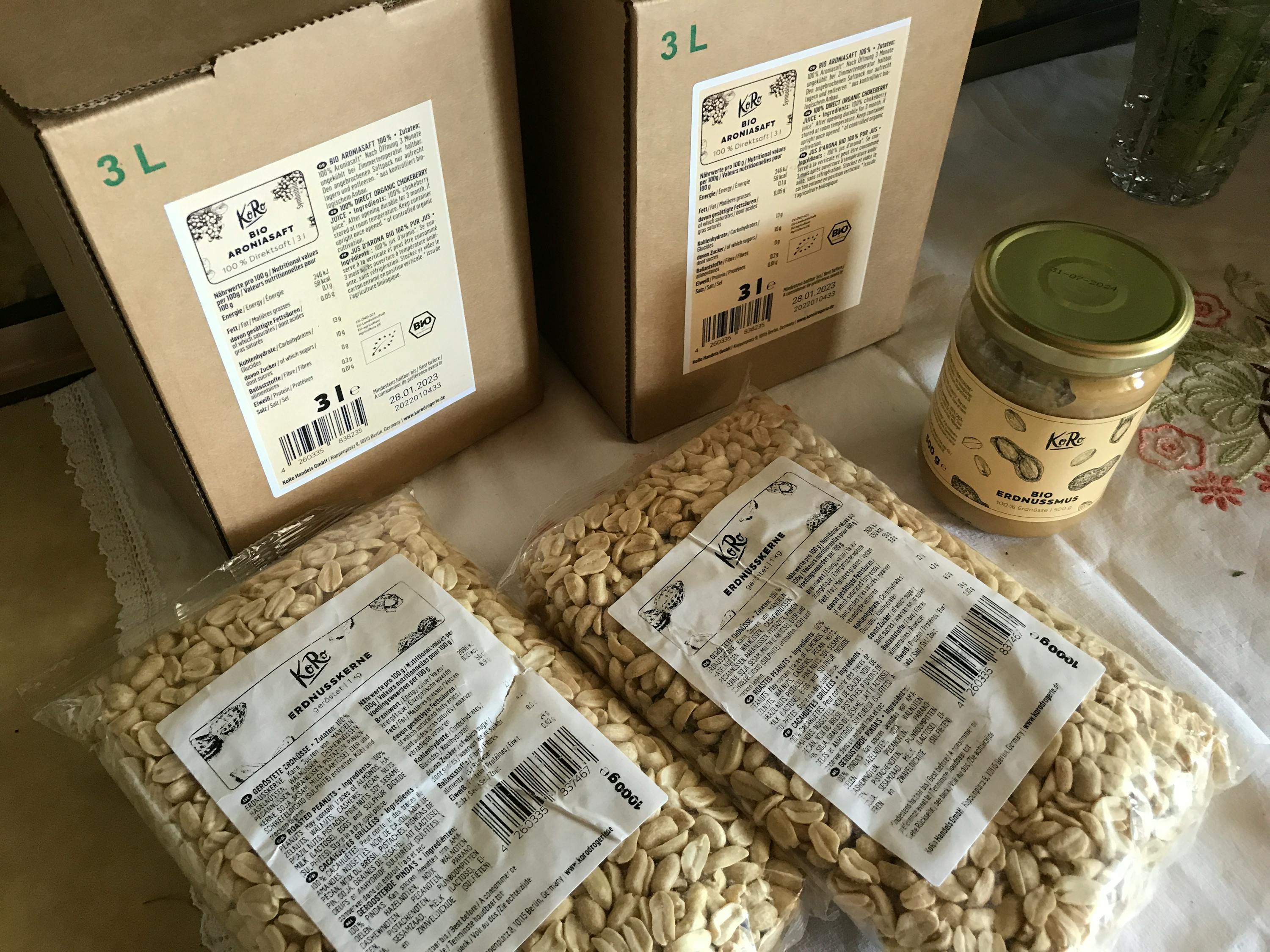 trois sacs de cacahuètes sont assis à côté d' une bouteille de sauce de cacahuètes