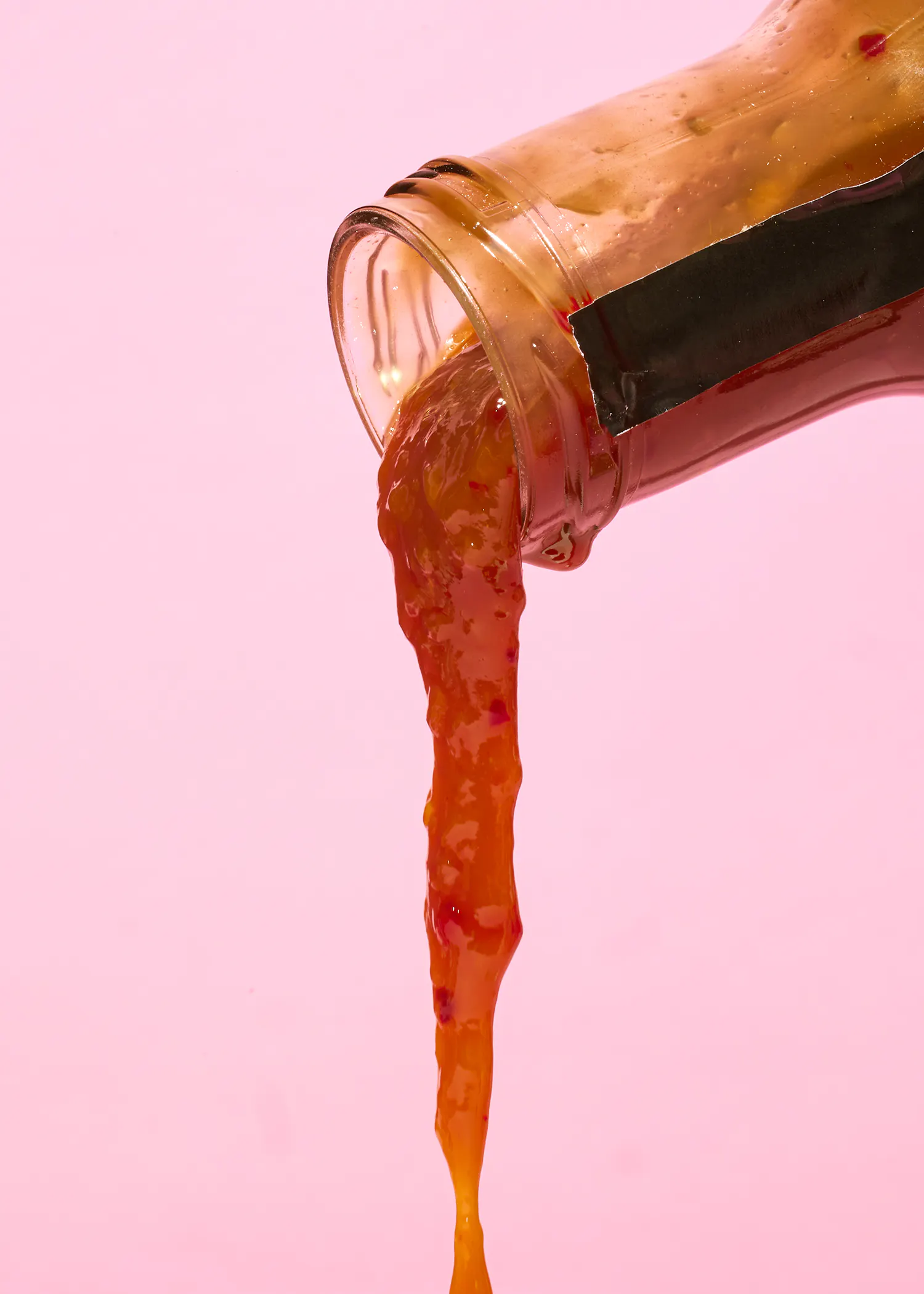 une bouteille de ketchup est versée sur une surface rose