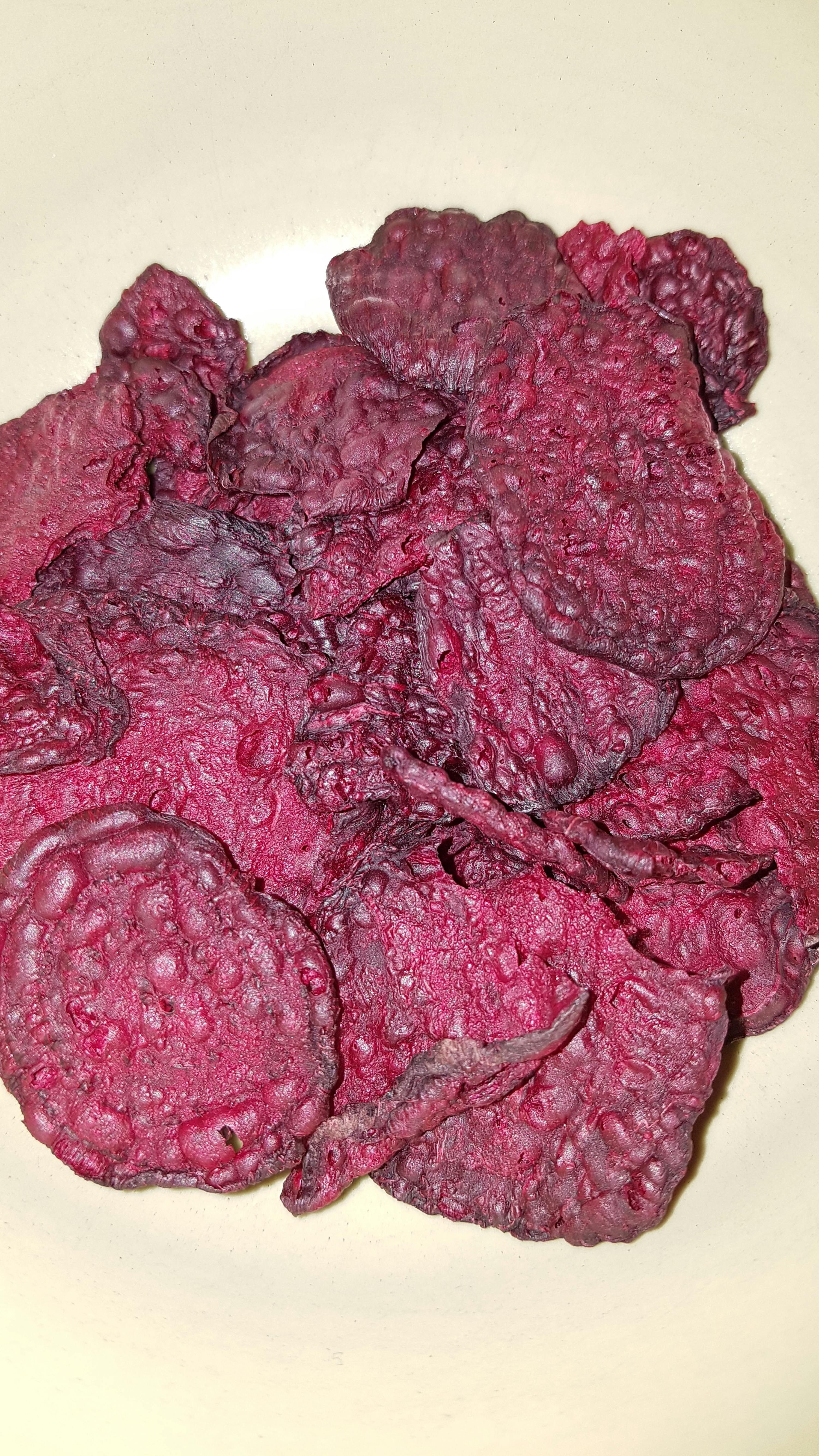 ein weißer Teller mit einem Haufen lila Kartoffelchips darauf