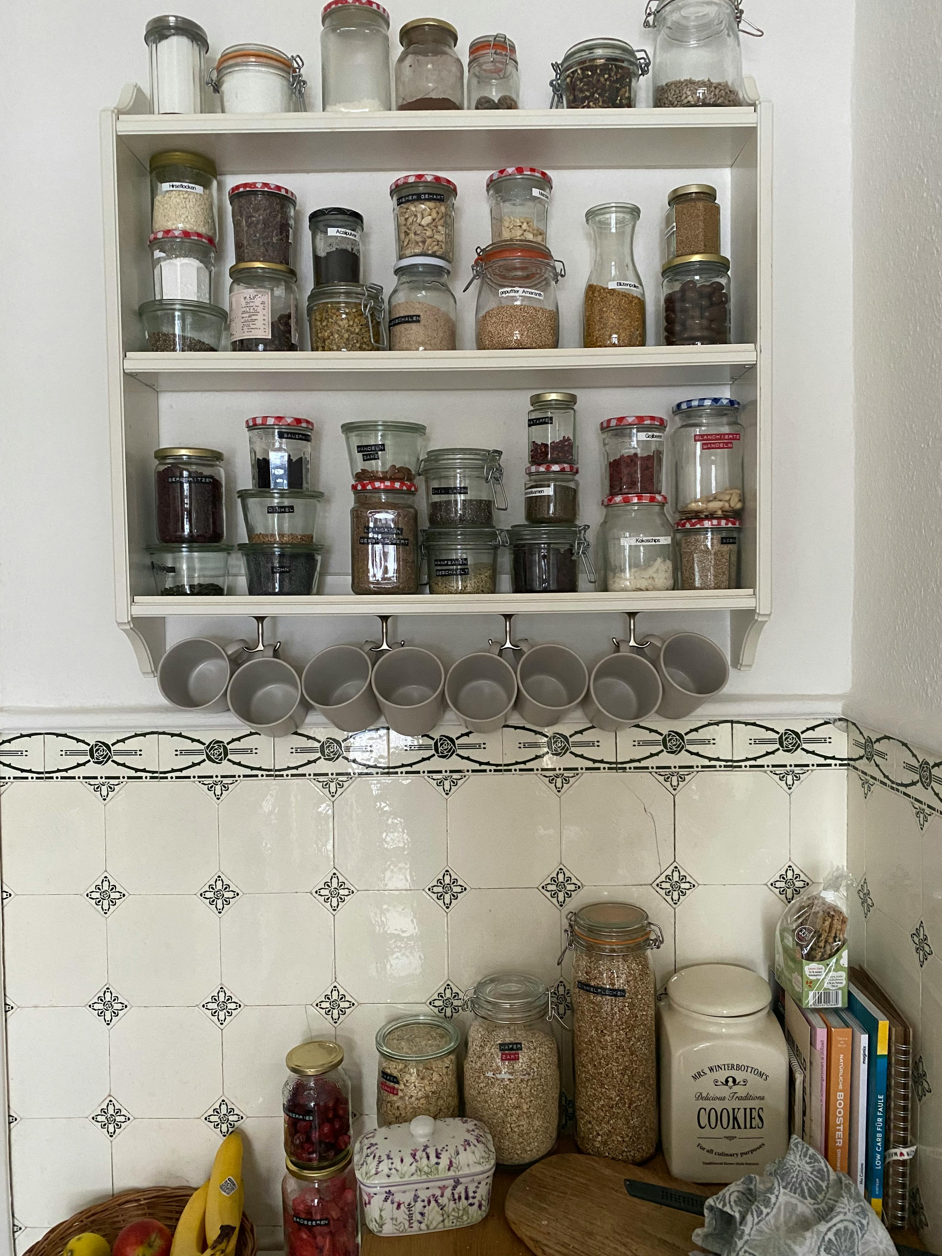 eine Reihe von Gläsern und Tassen auf einem Regal neben einem Glasgefäß mit der Aufschrift " cookies "