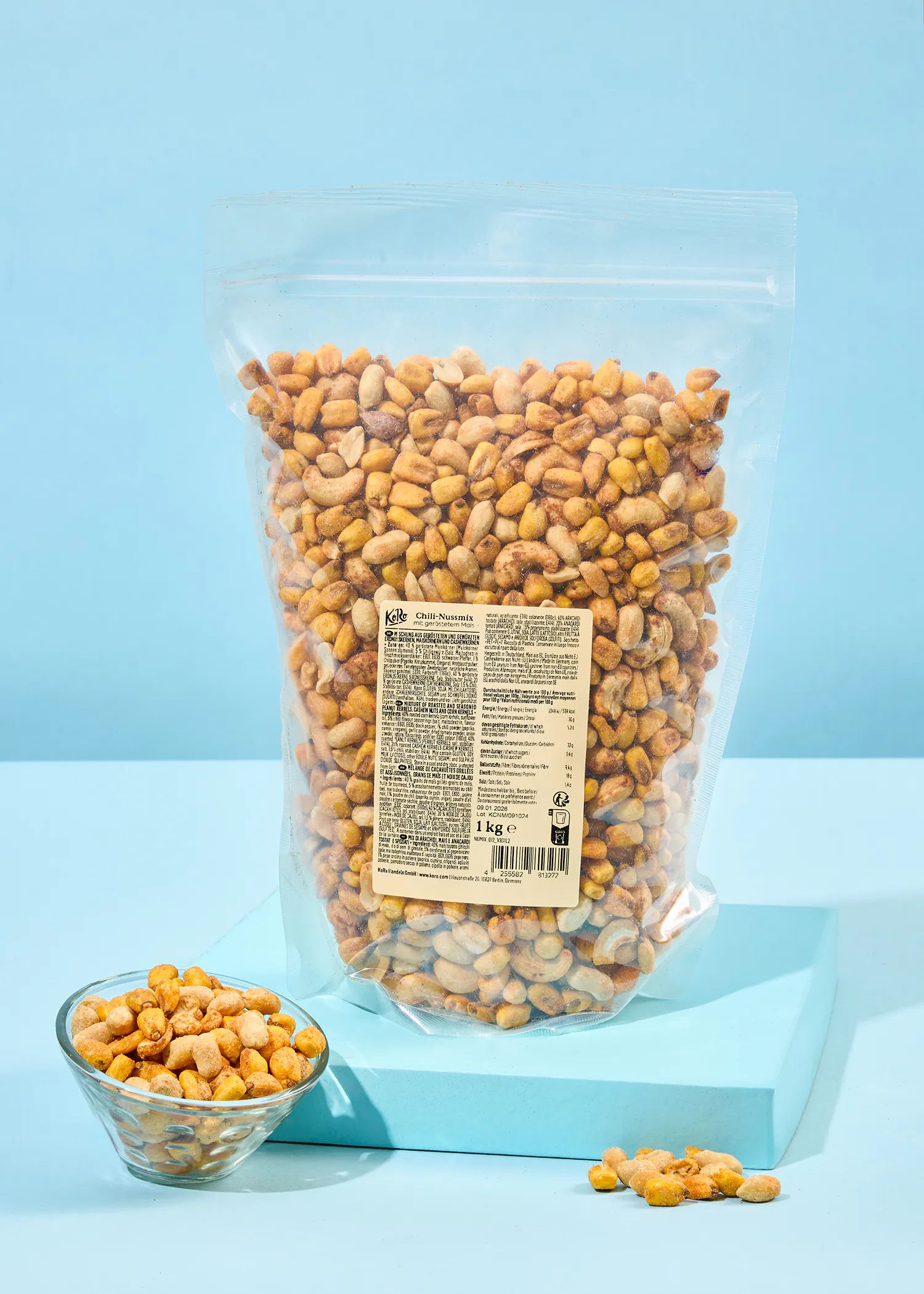 eine Tüte gerösteten Erdnüsse steht neben einer Glasschale mit Erdnüssen