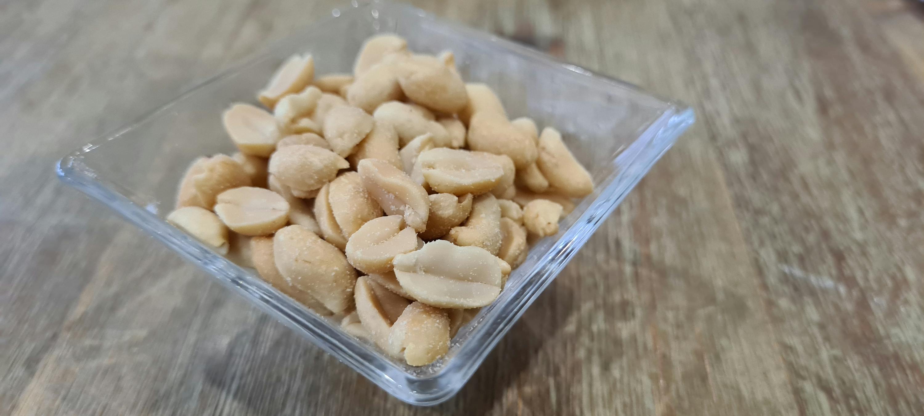 una ciotola di arachidi è seduta su un tavolo di legno