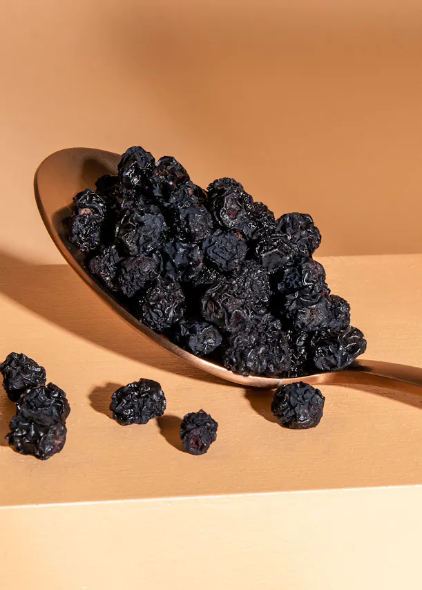 a metal spoon filled with dried blueberries on a table