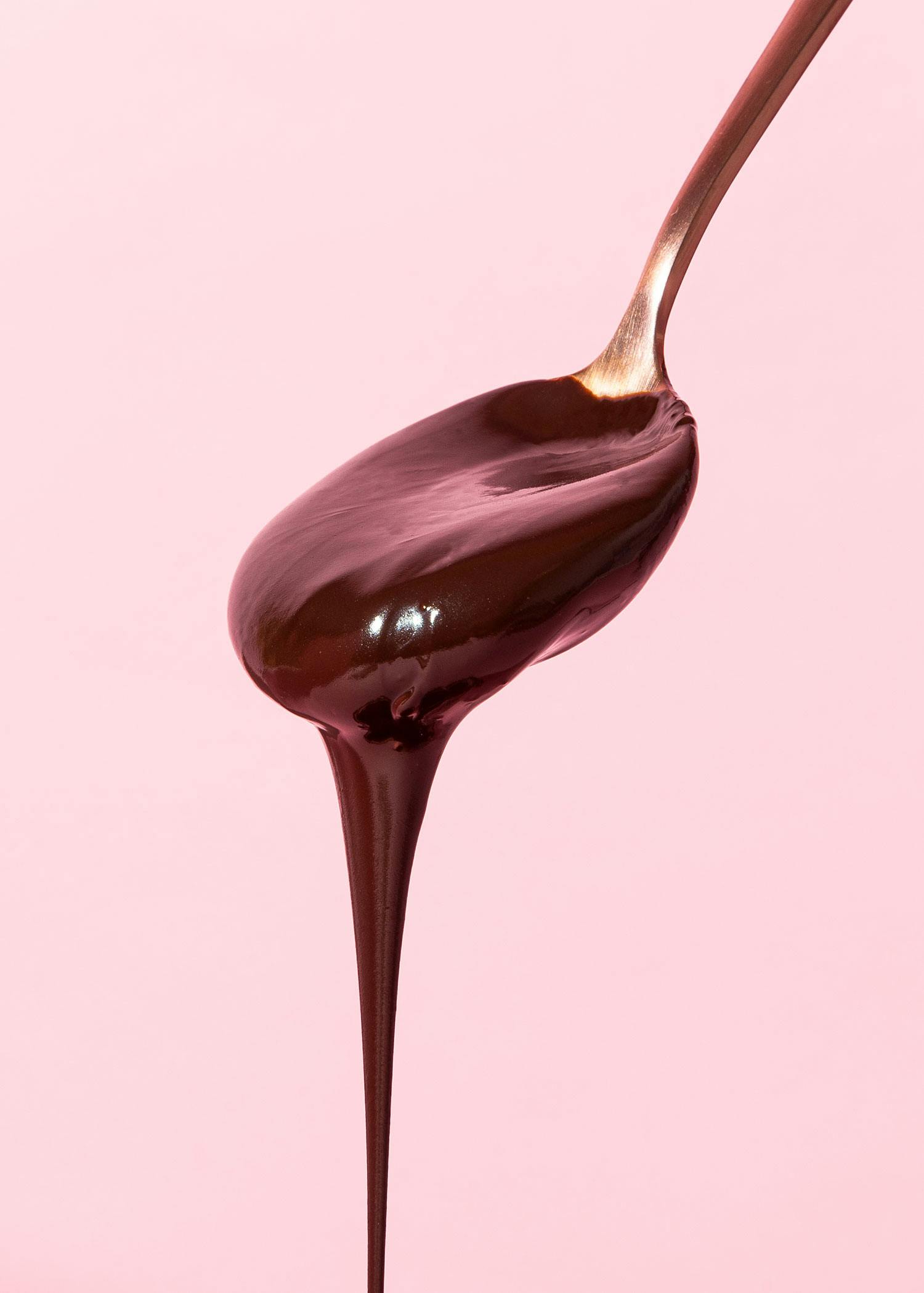un cucchiaio pieno di cioccolato su sfondo rosa