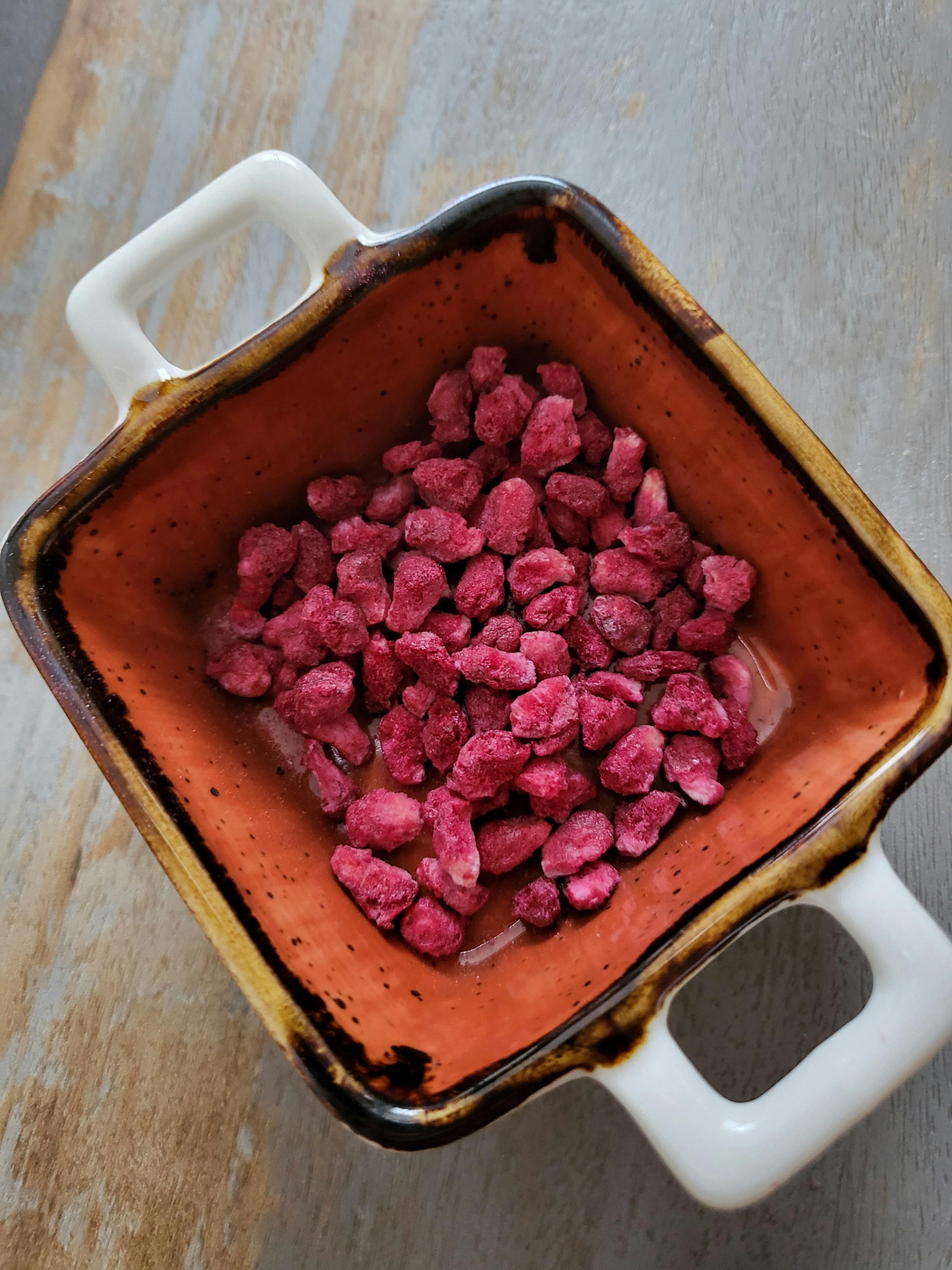 a brown and white bowl filled with pink candy