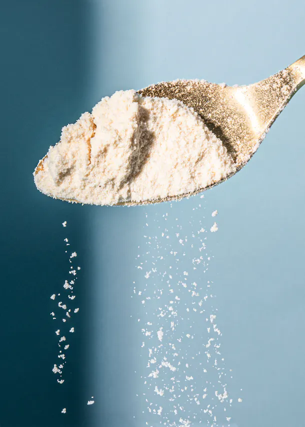 a gold spoon filled with white powder on a blue background