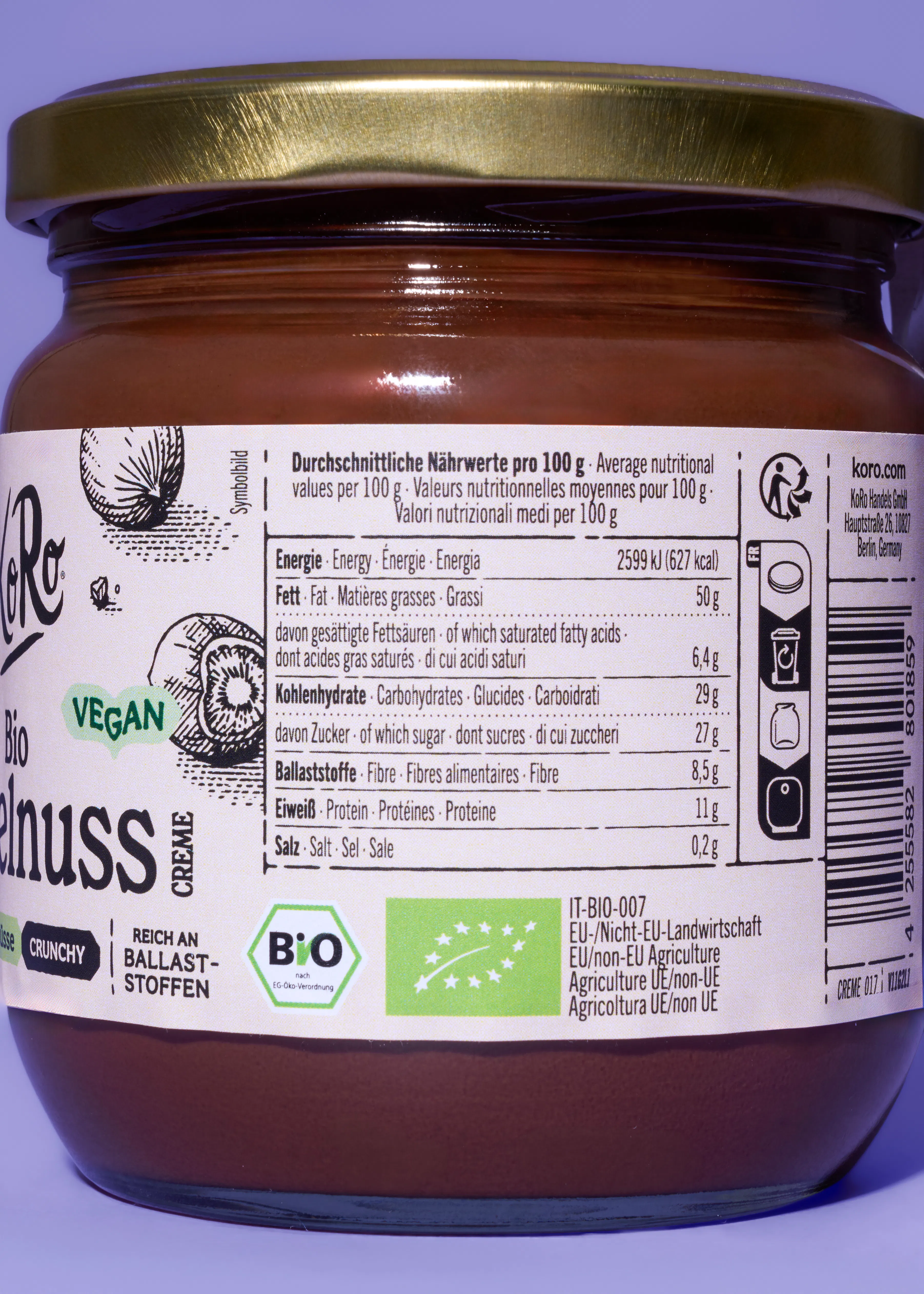 ein glas mit brauner nusscreme und goldenem deckel, dessen etikett nährwertangaben, vegan- und bio-siegel sowie die marke koro zeigt.