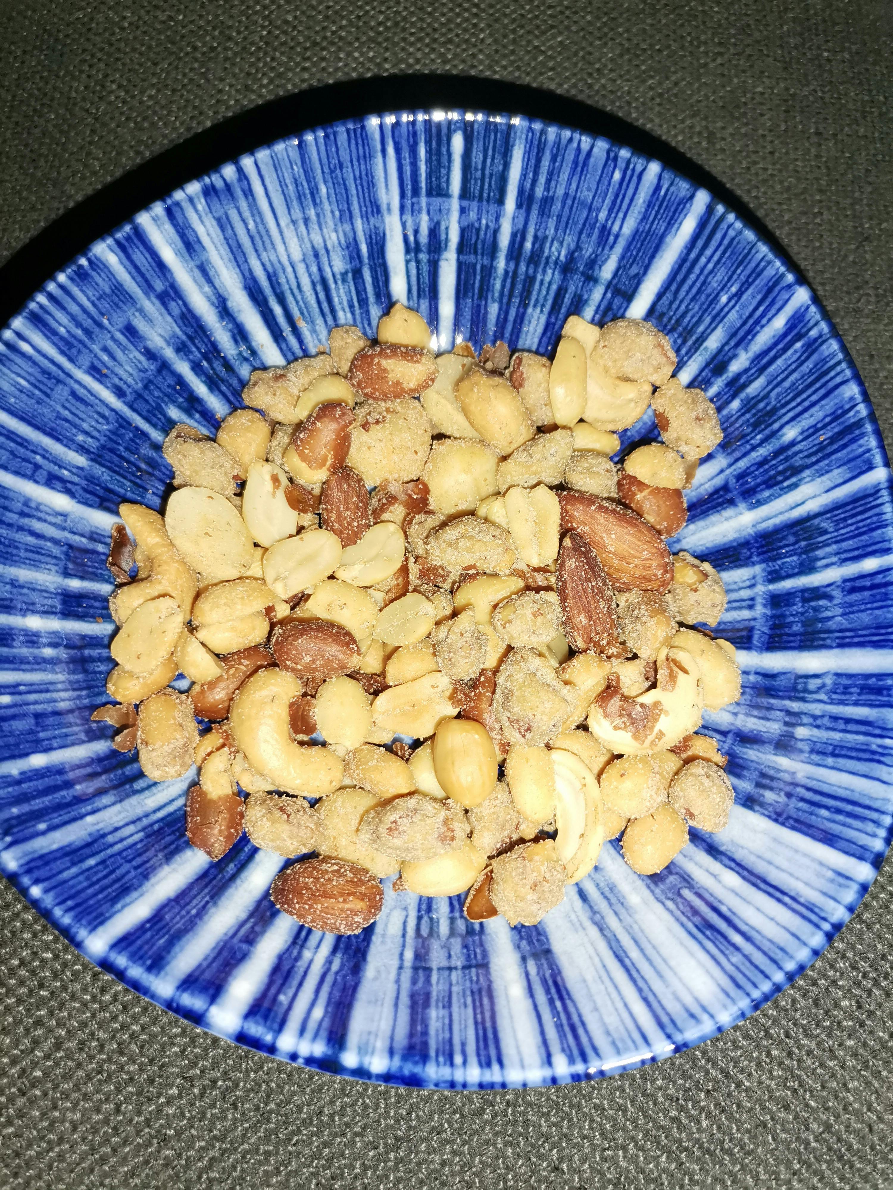 un piatto blu e bianco pieno di arachidi e mandorle