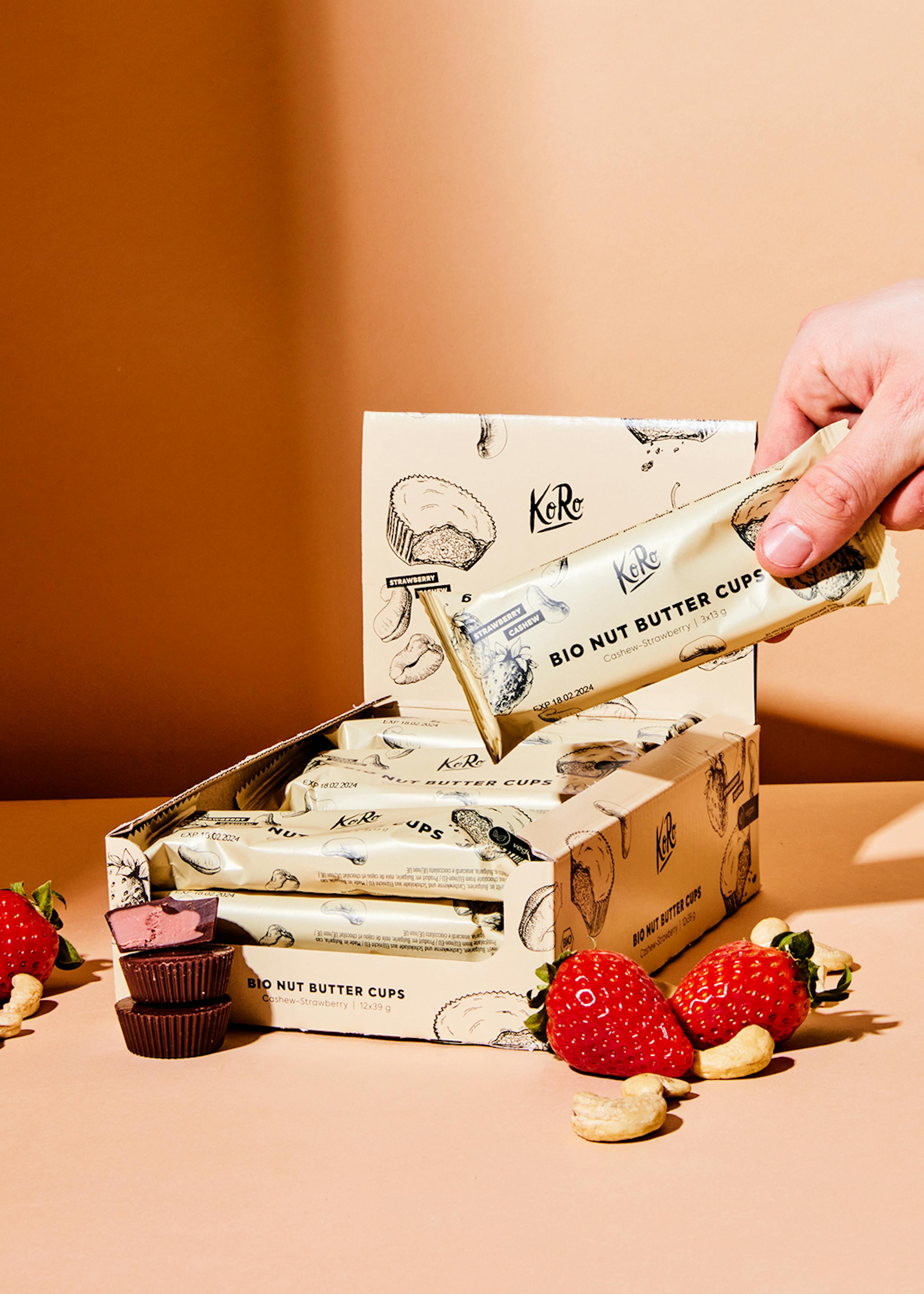 Eine Person hält einen Keks in der Hand neben einer Schachtel Kekse