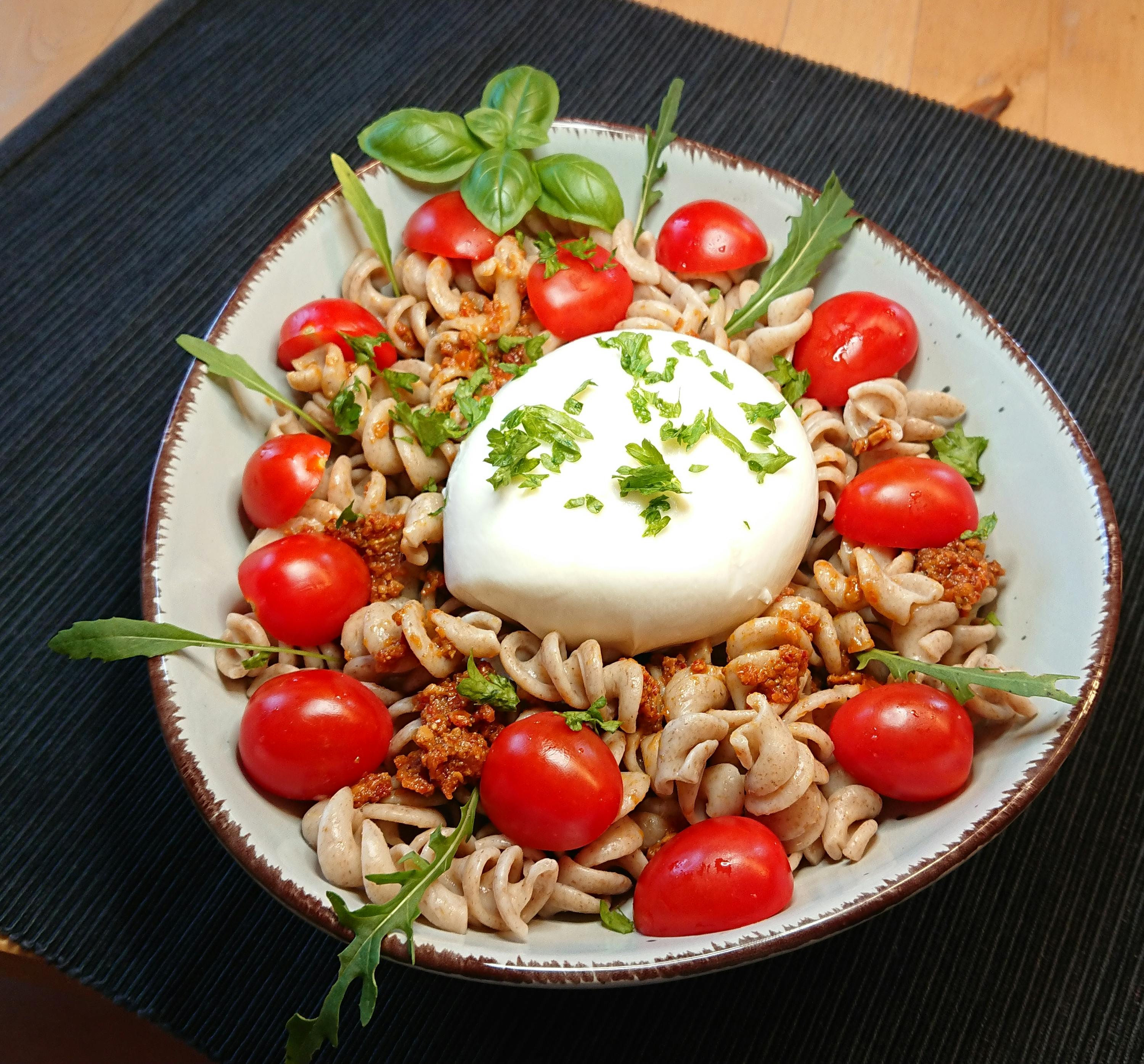una ciotola di pasta con pomodori e mozzarella su un tavolo