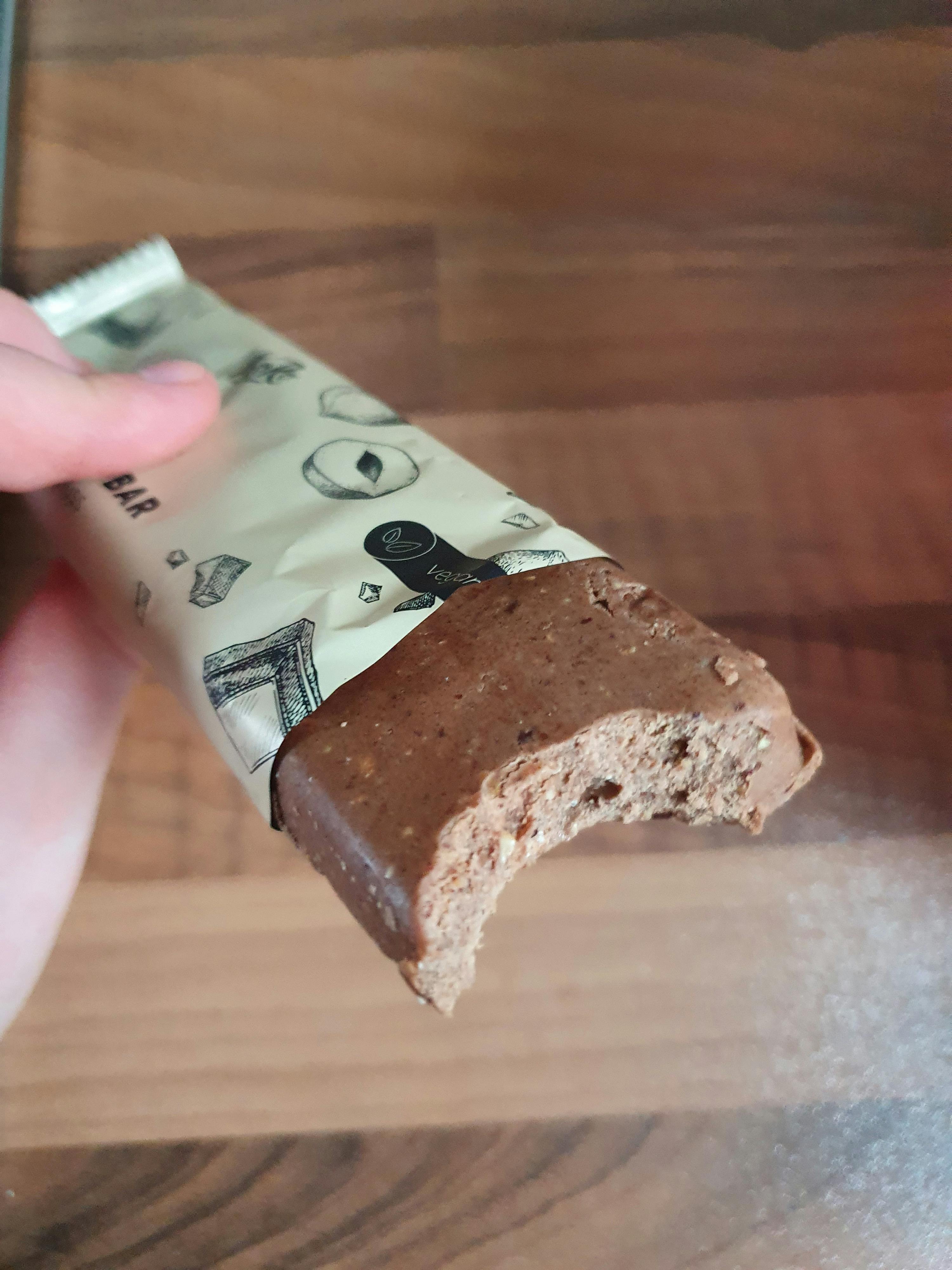 Eine Person hält eine Schokoladenstange mit einem Stück genommen