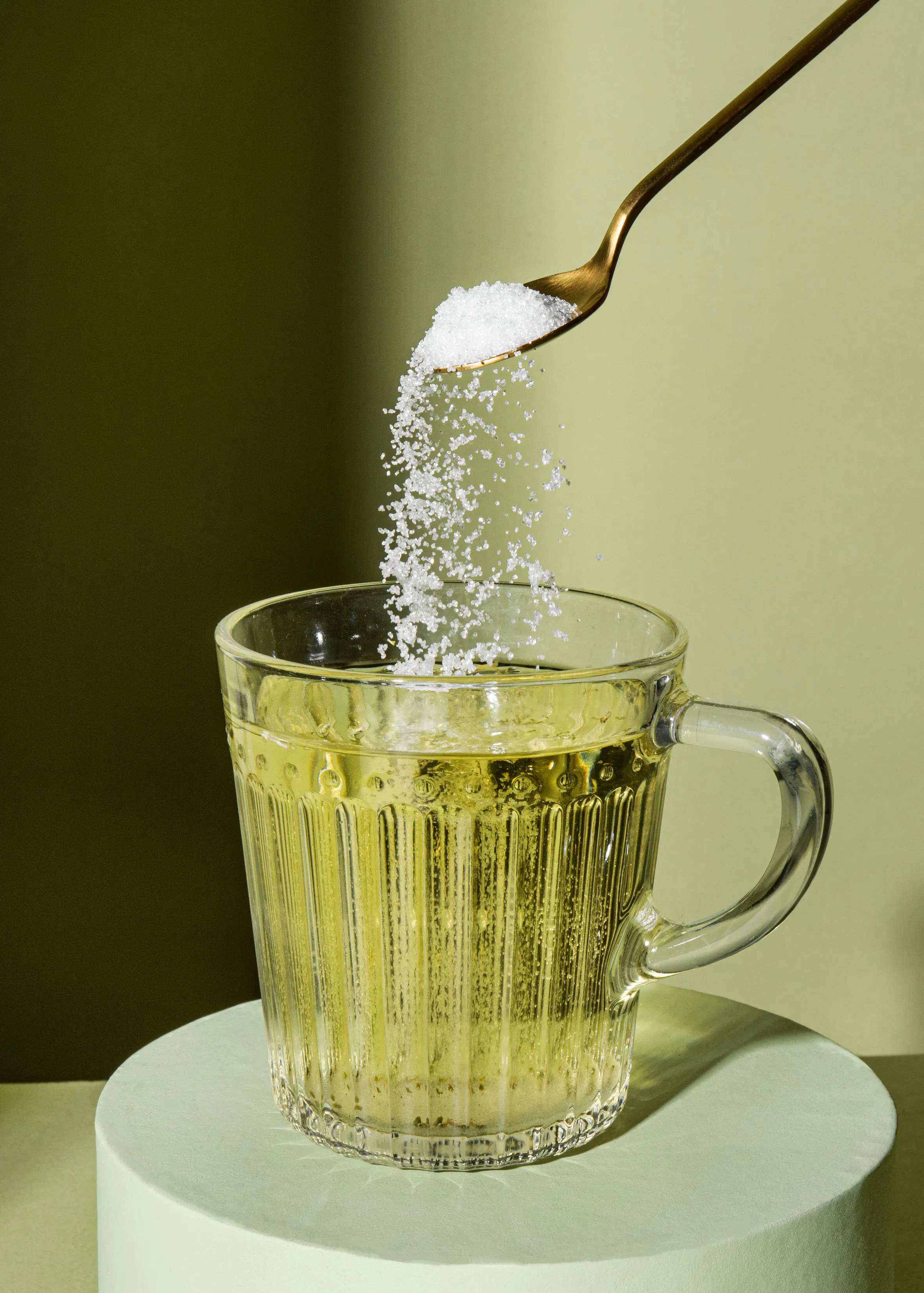 a spoon is pouring sugar into a cup of liquid