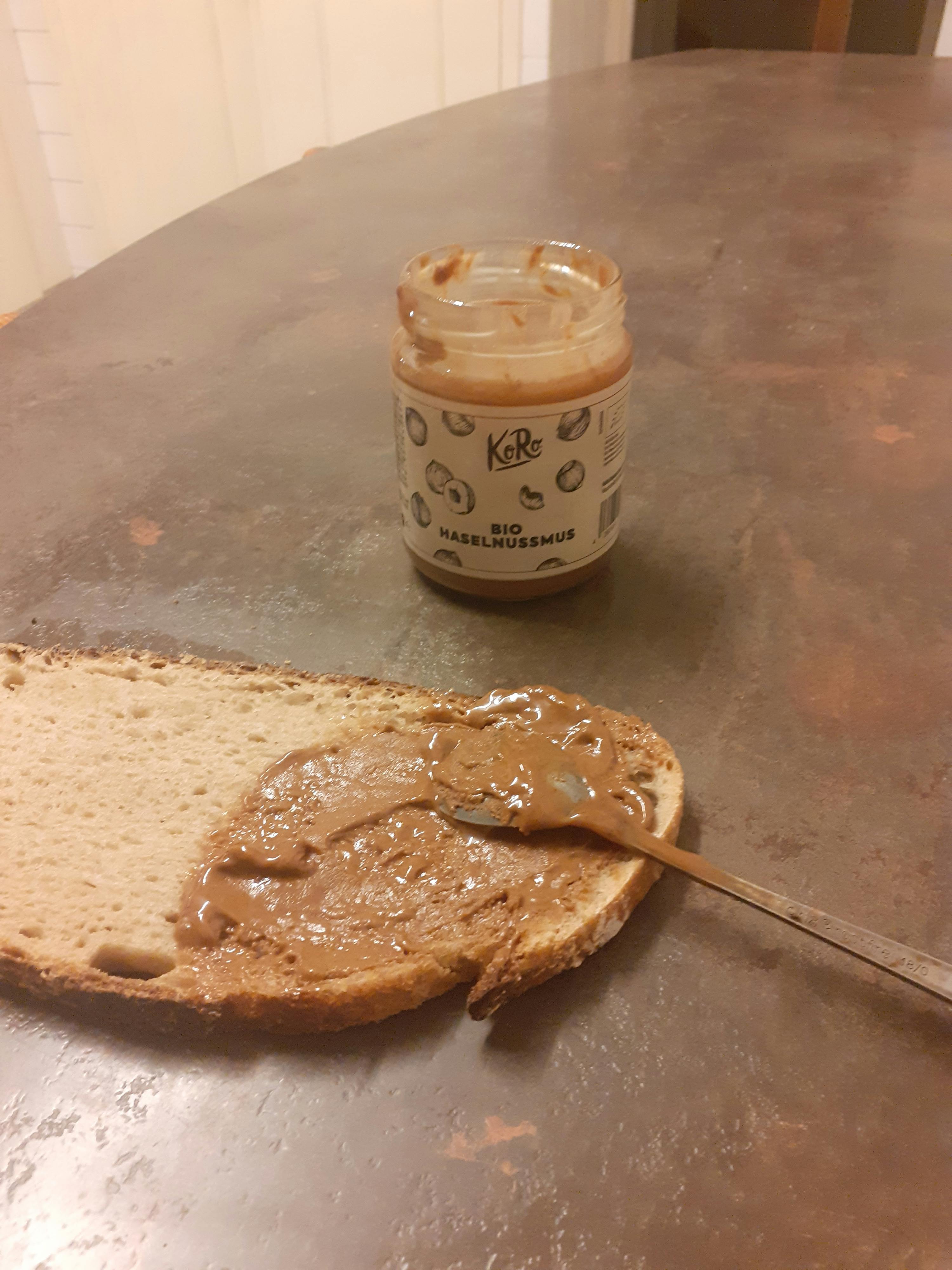 ein Stück Brot mit Erdnussbutter auf einem Tisch neben einer Dose Erdnussbutter