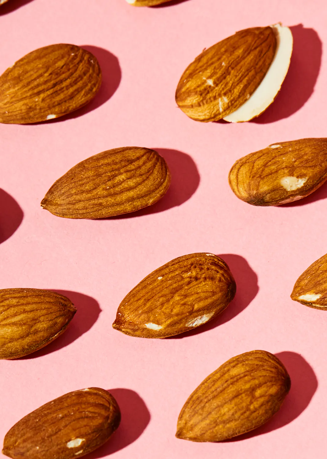 les amandes sont disposées en rangées sur un fond rose