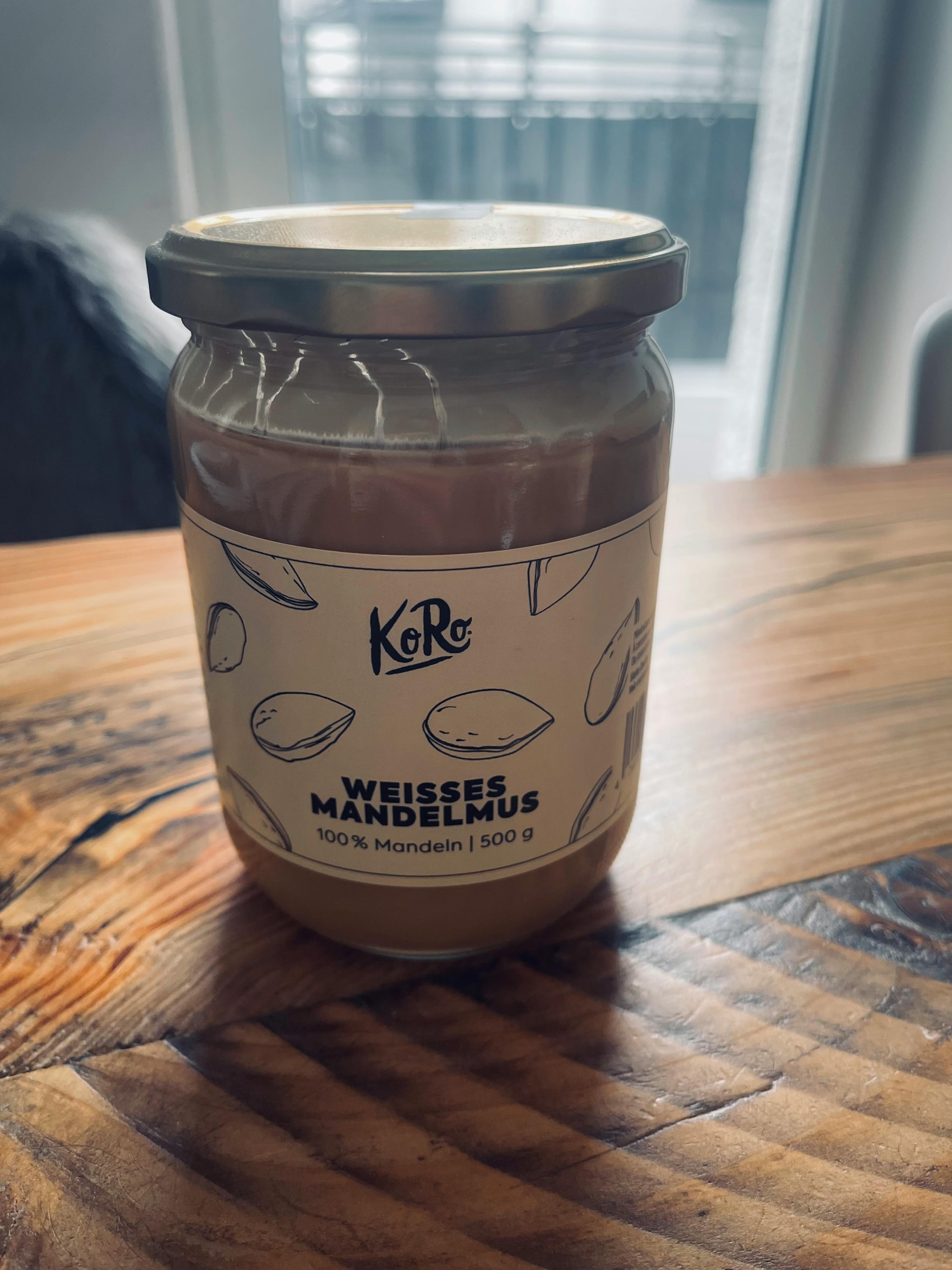 un barattolo di burro di mandorle bianco è seduto su un tavolo di legno