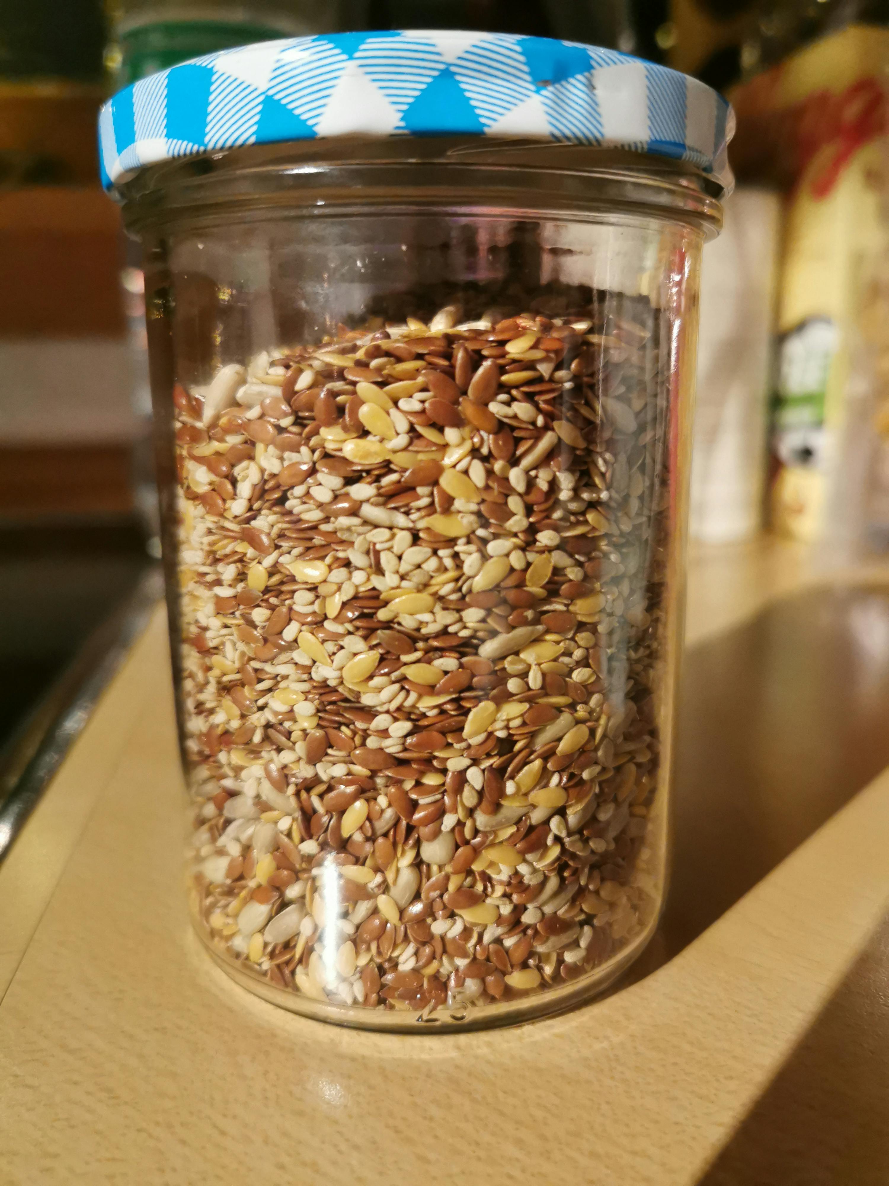 ein Glas voller verschiedener Samen mit einem blau karierten Deckel