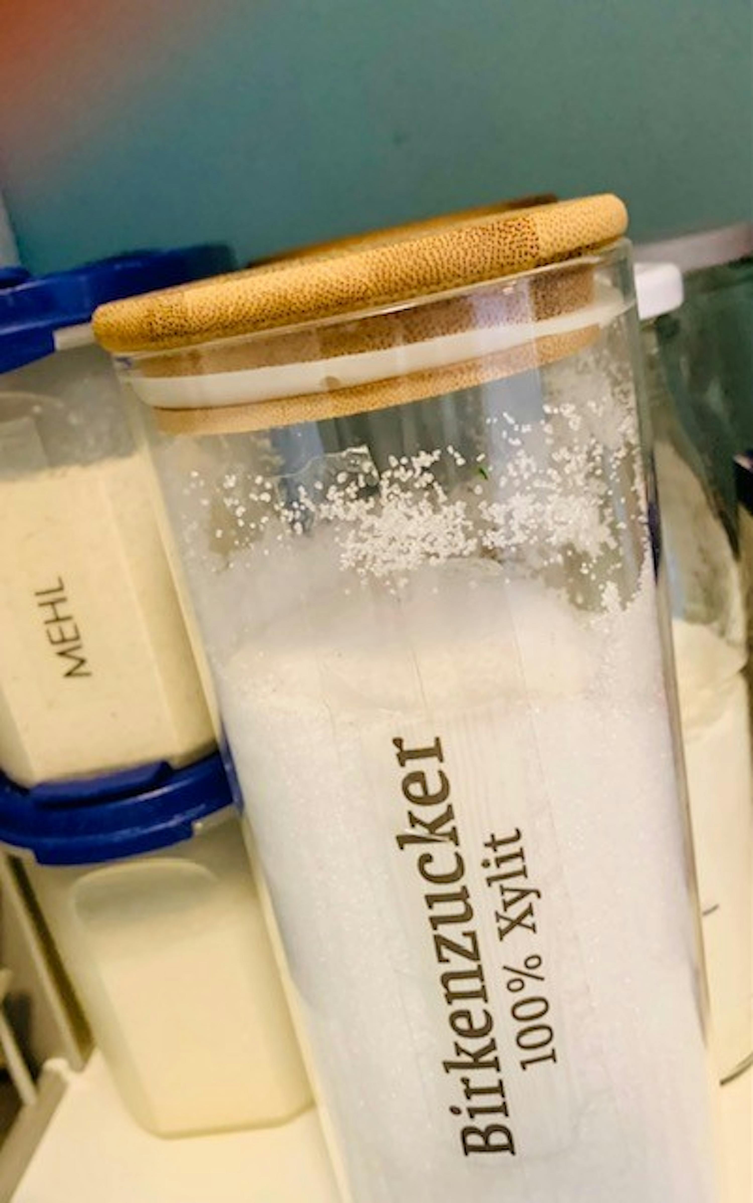 a glass jar filled with birkenzucker and xylitol is sitting on a counter .