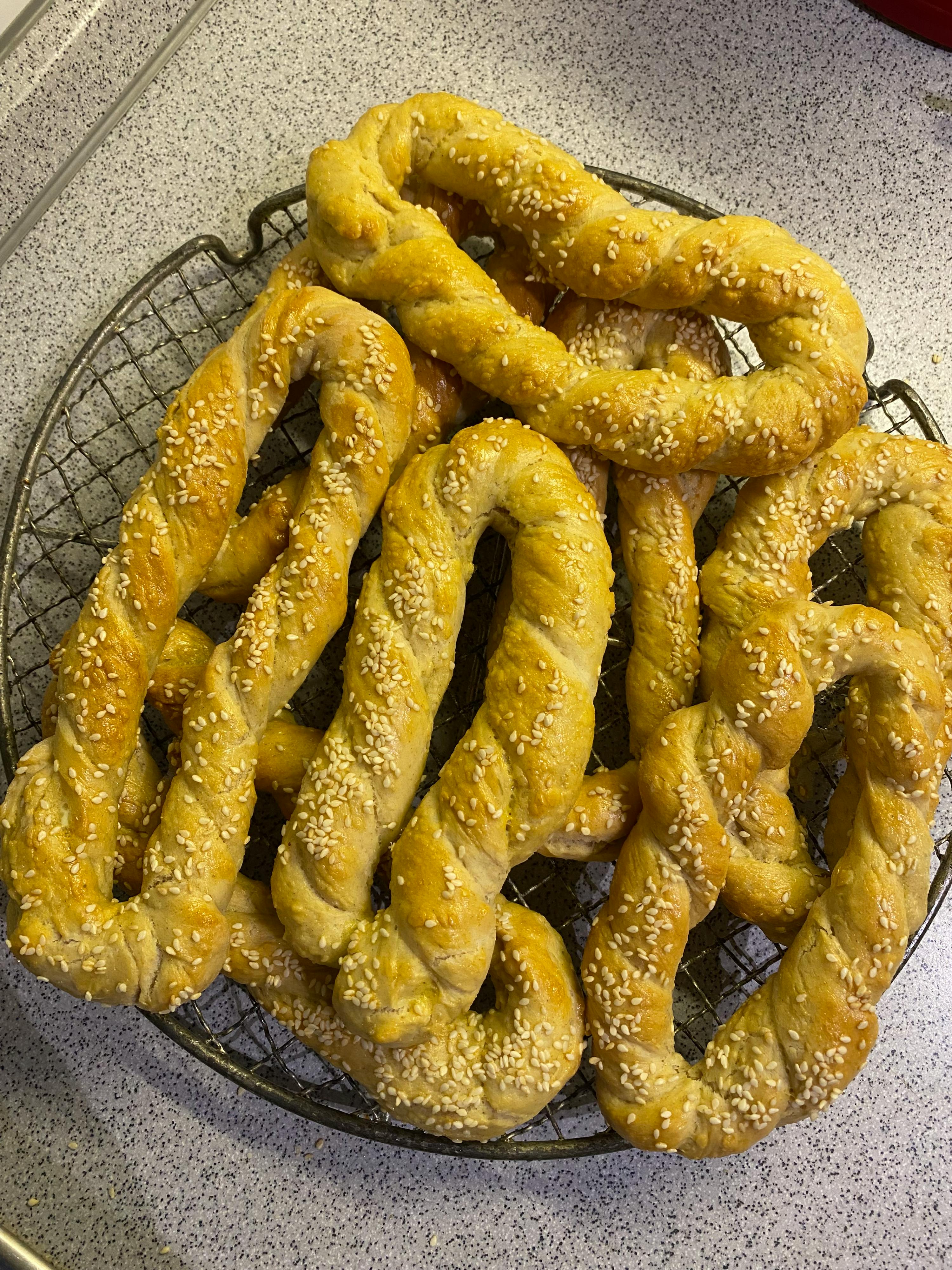 un tas de bretzels avec des graines de sésame sur une grille de refroidissement