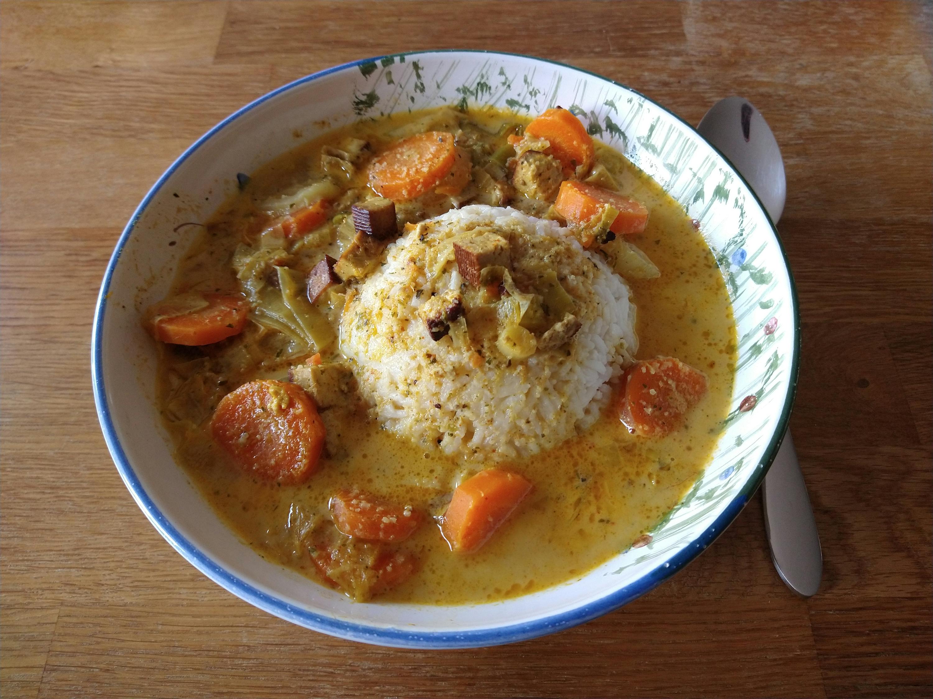 a bowl of soup with carrots and rice on top